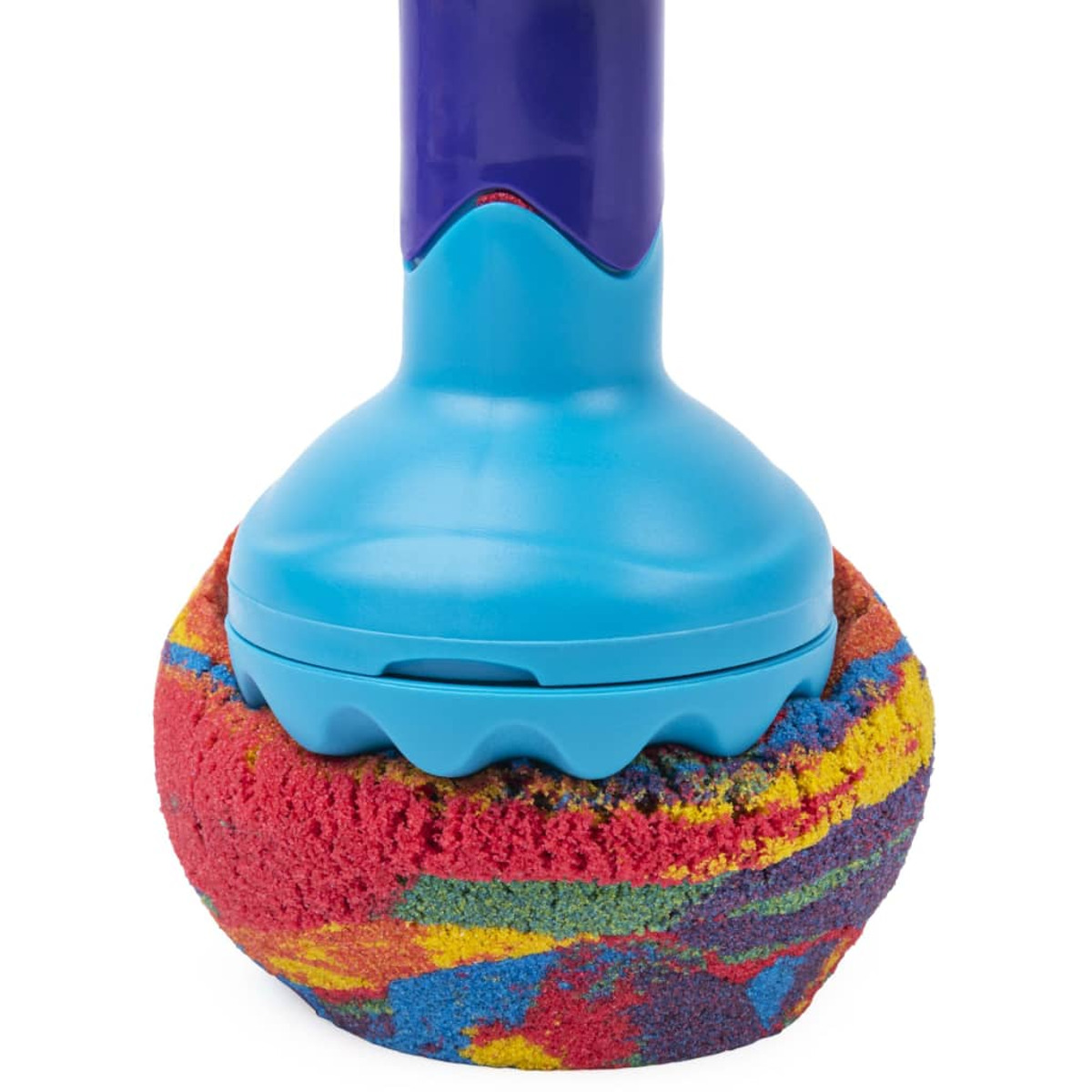 Un jouet bleu au-dessus d'une boule de sable colorée sur un fond blanc.