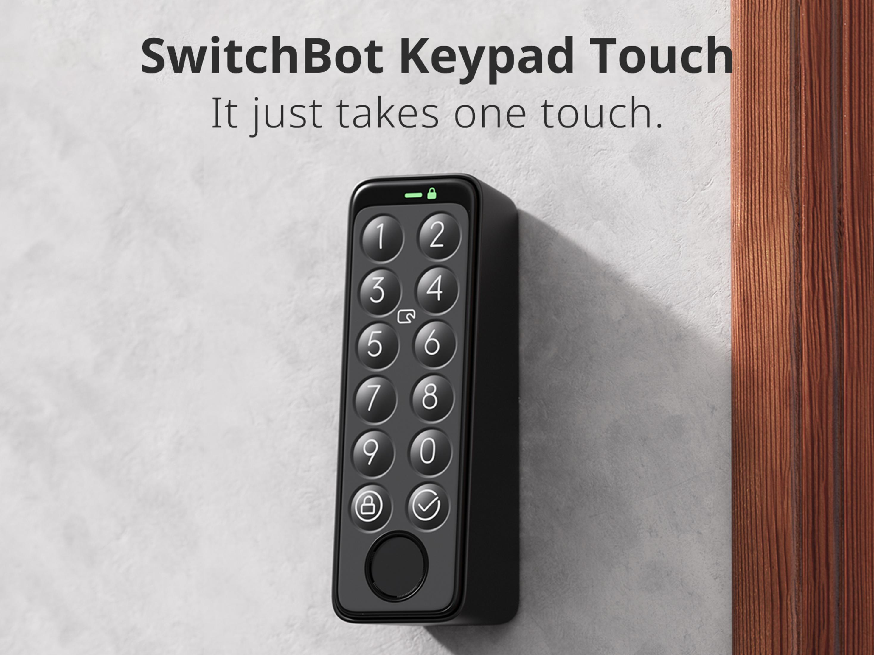 Eine SwitchBot Keypad Touch an einer hellgrauen Wand neben einem hölzernen Türrahmen.