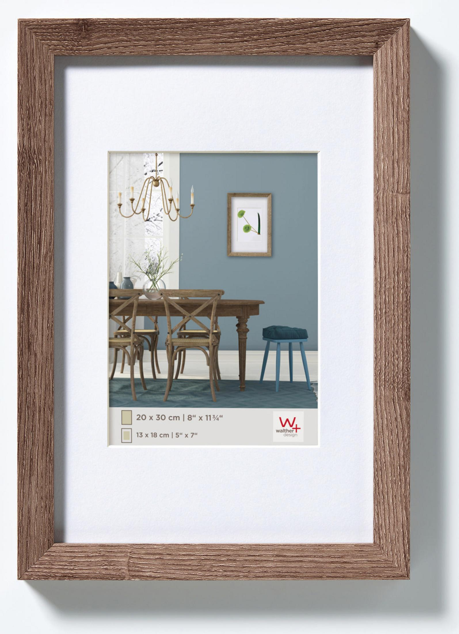 Un'immagine incorniciata mostra una scena della sala da pranzo. Sono visibili un tavolo, sedie e un lampadario.