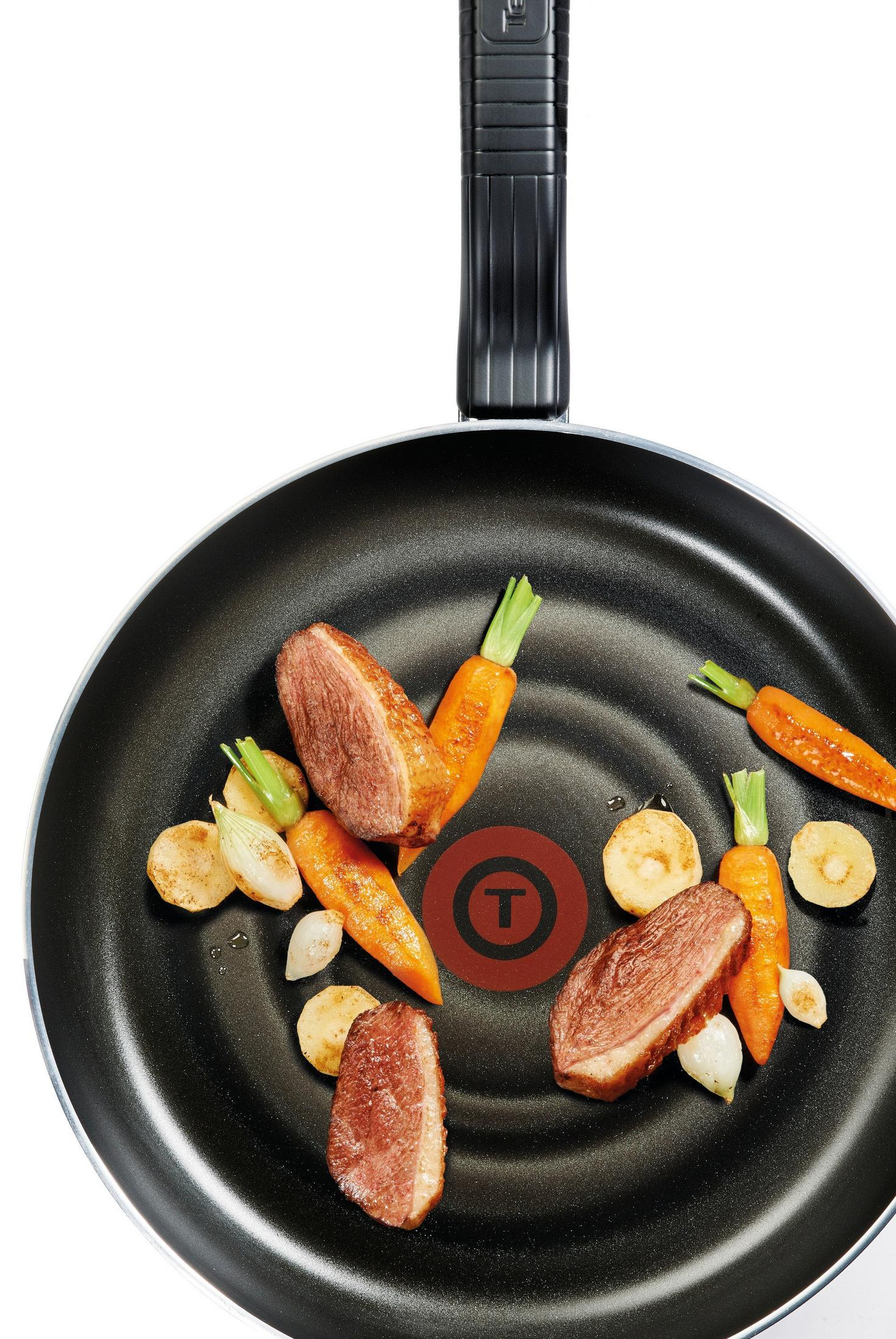 Bratpfanne mit geschnittener Entenbrust, Karotten und Kartoffeln auf weißem Hintergrund.