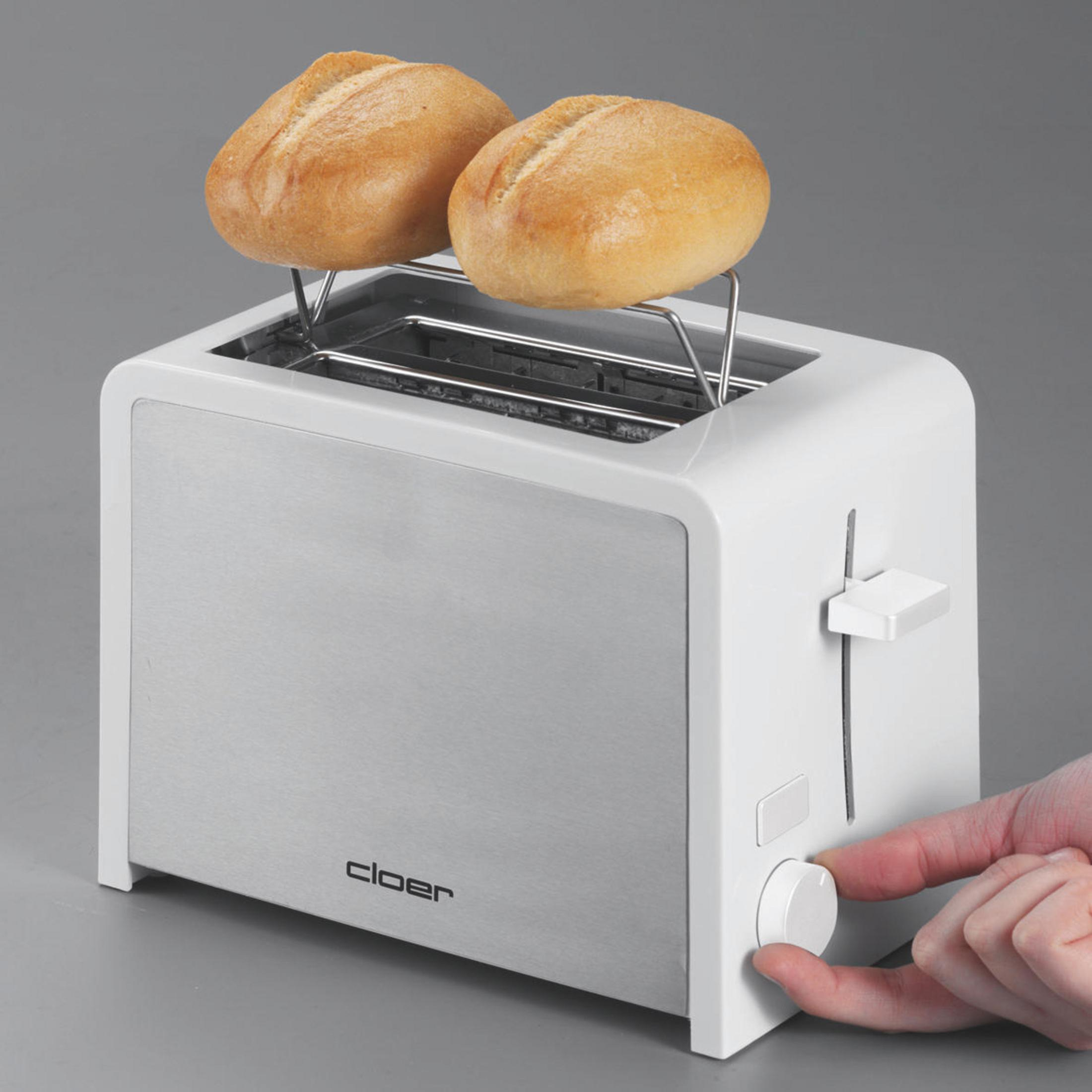 Mani che usano un tostapane argento e bianco per tostare panini su grigio.