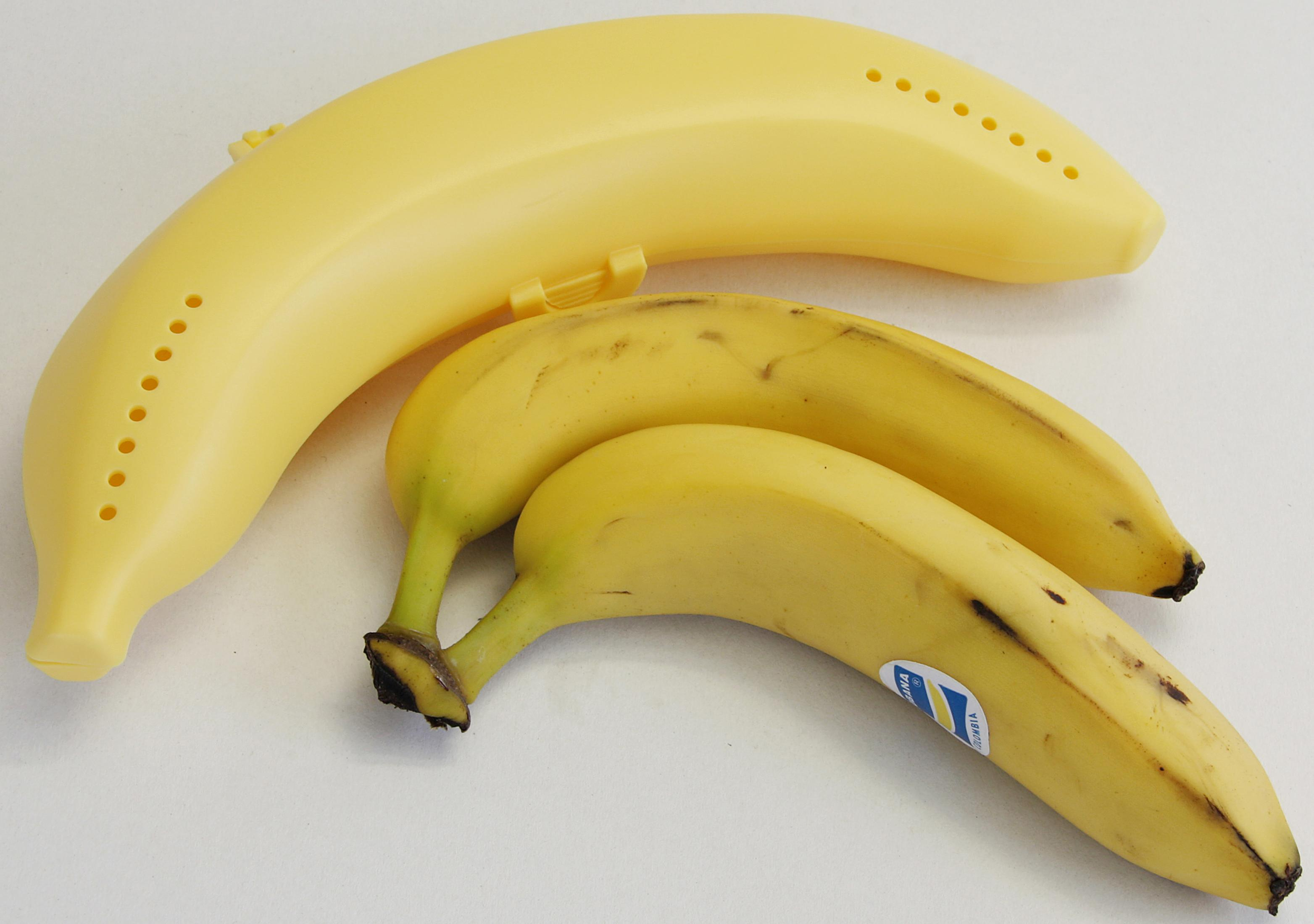 Eine gelbe Bananentasche neben zwei Bananen. Eine ist in der Tasche.