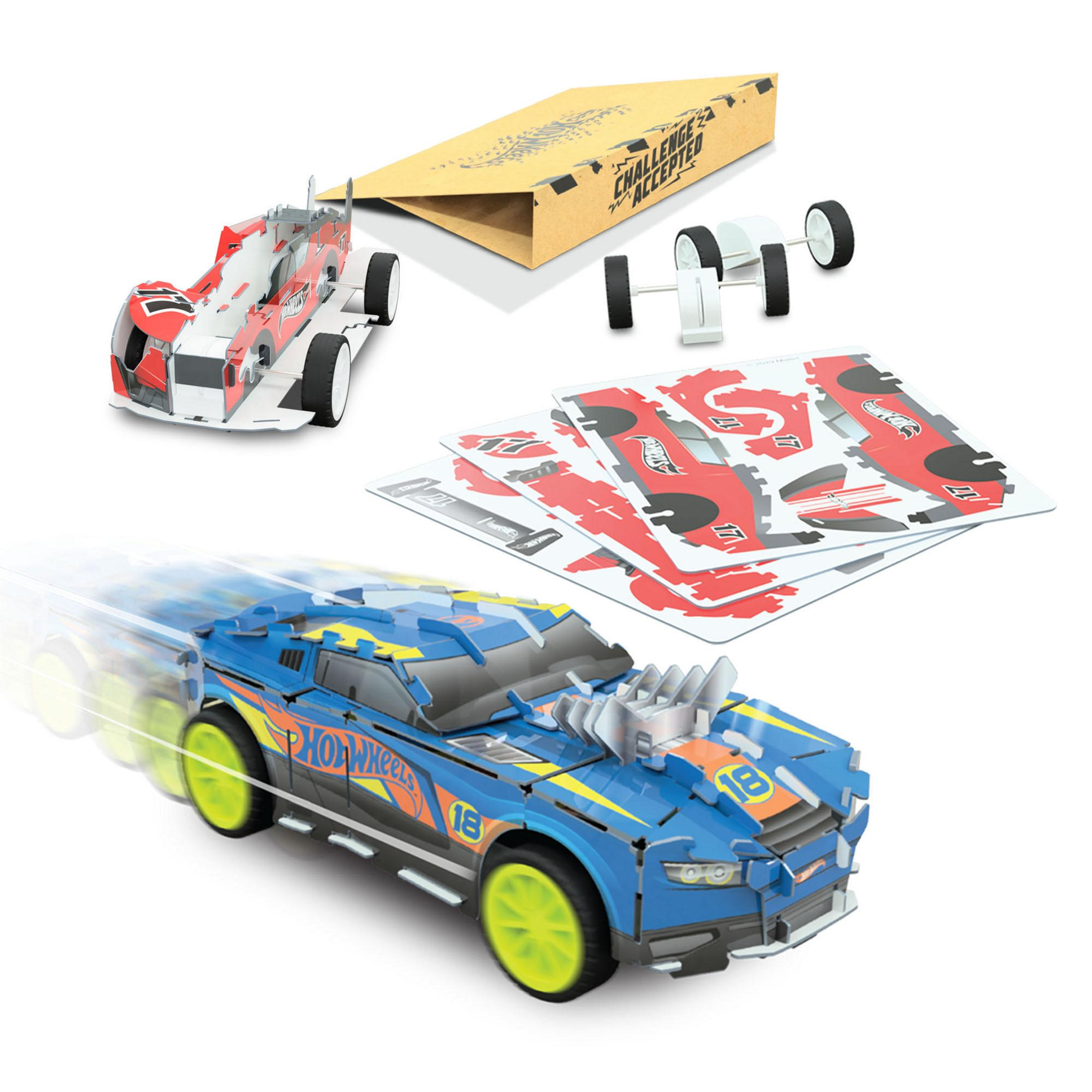 Ein blaues Hot Wheels Auto mit lindgrünen Reifen, ein Karton und rot-weiße gestanzte Autoteile stehen auf einer weißen Fläche.