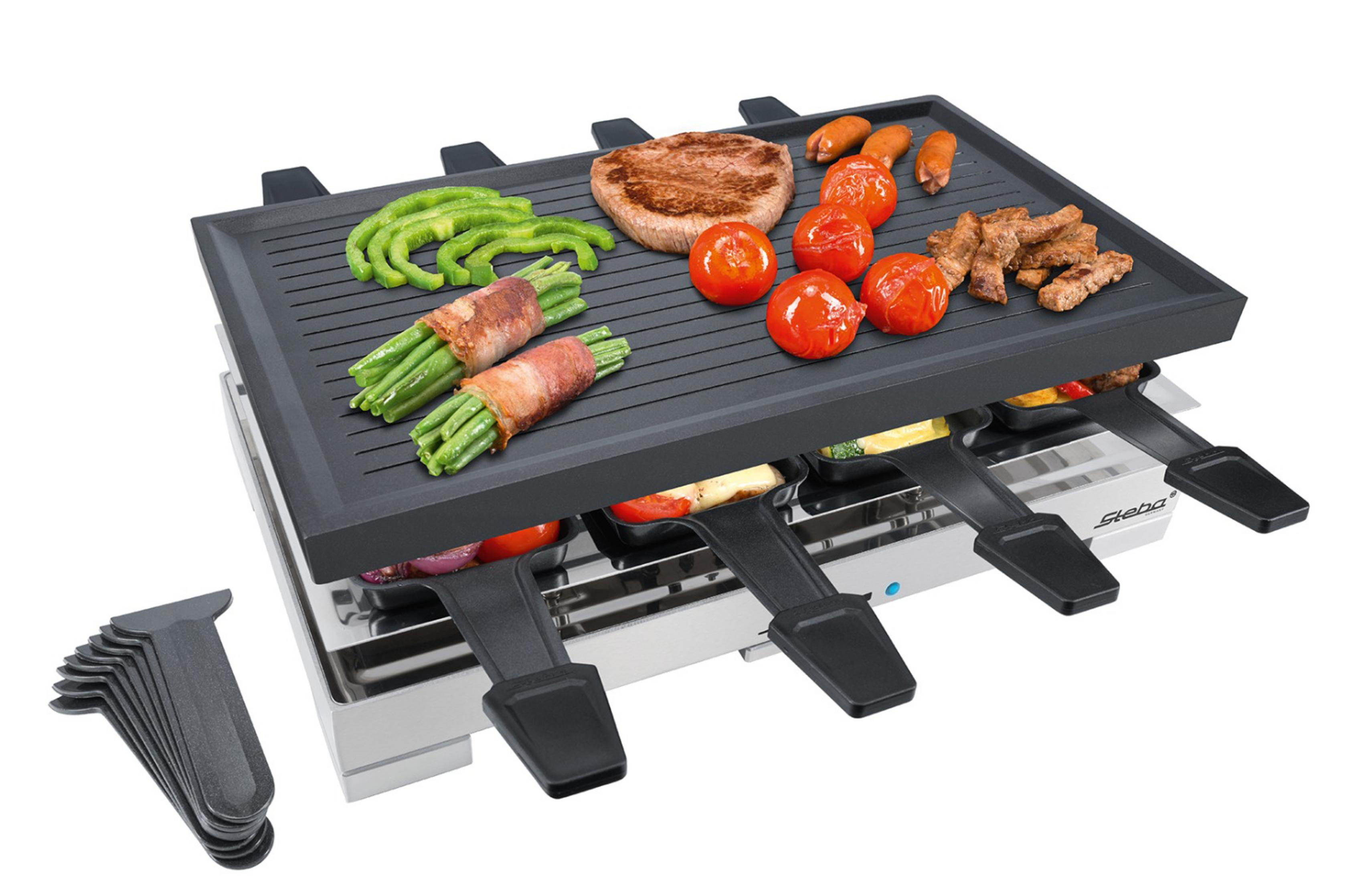 Una griglia per raclette con carne, verdure e formaggio che cuociono sopra, con utensili accanto.