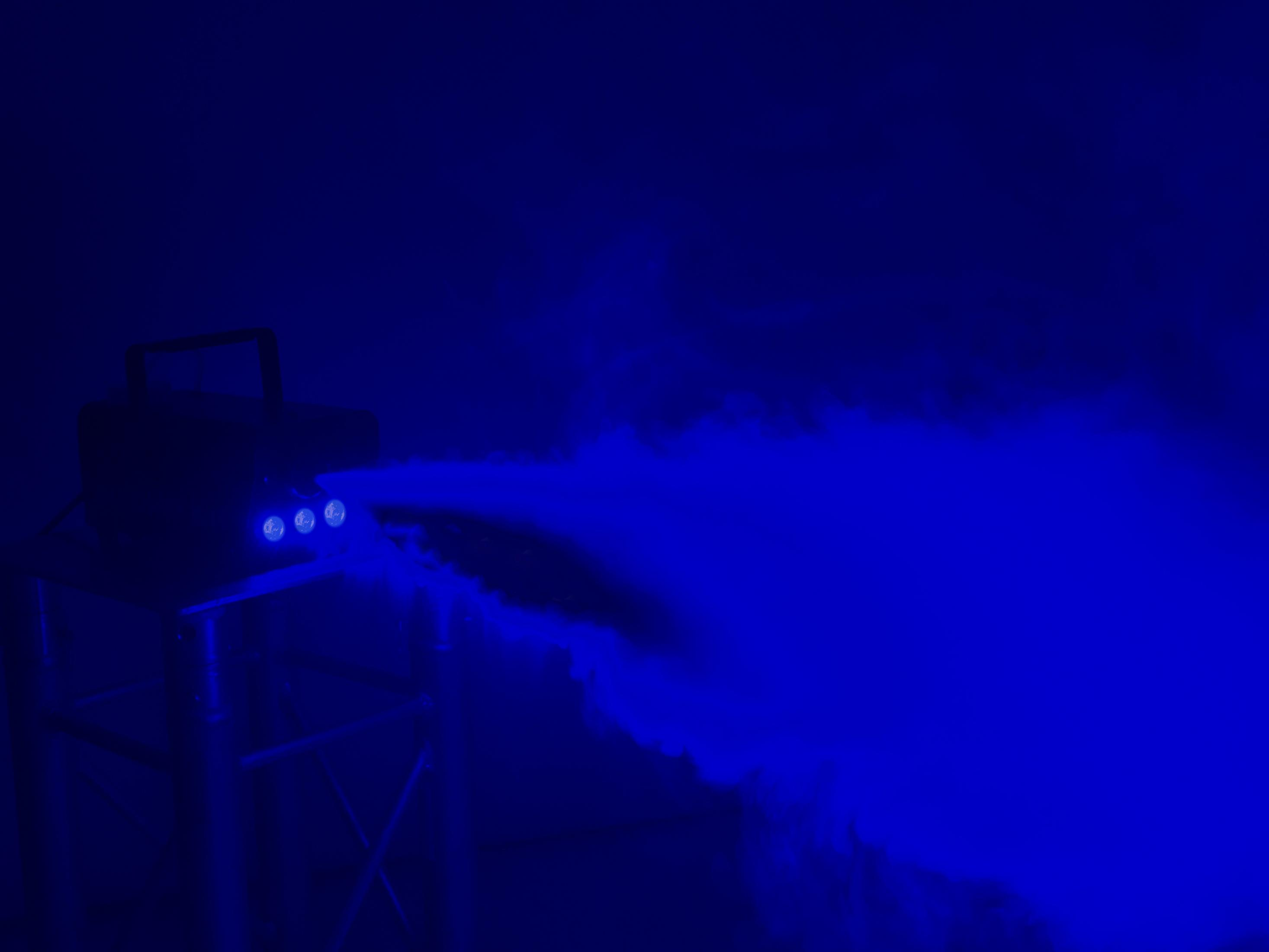 Nebelmaschine, die blauen Rauch mit blauen Lichtern auf weißem Hintergrund ausstößt.