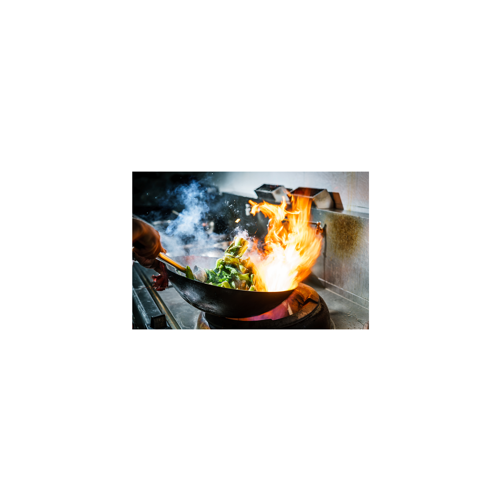 Uno chef cucina in un wok, con verdure e fiamme. Il fumo sale, in un ambiente cucina scuro.