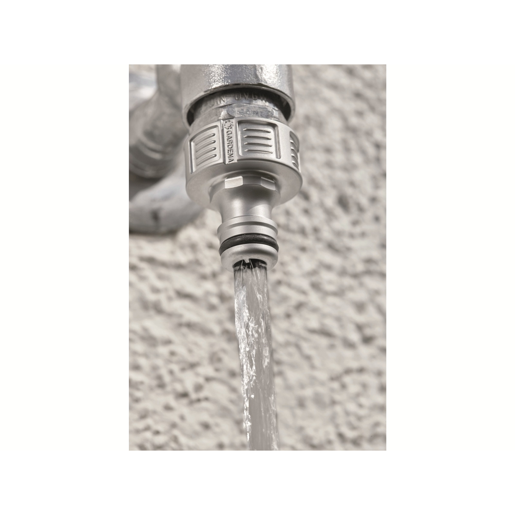 Un connettore per tubo flessibile Gardena collegato a un rubinetto con acqua che scorre fuori.