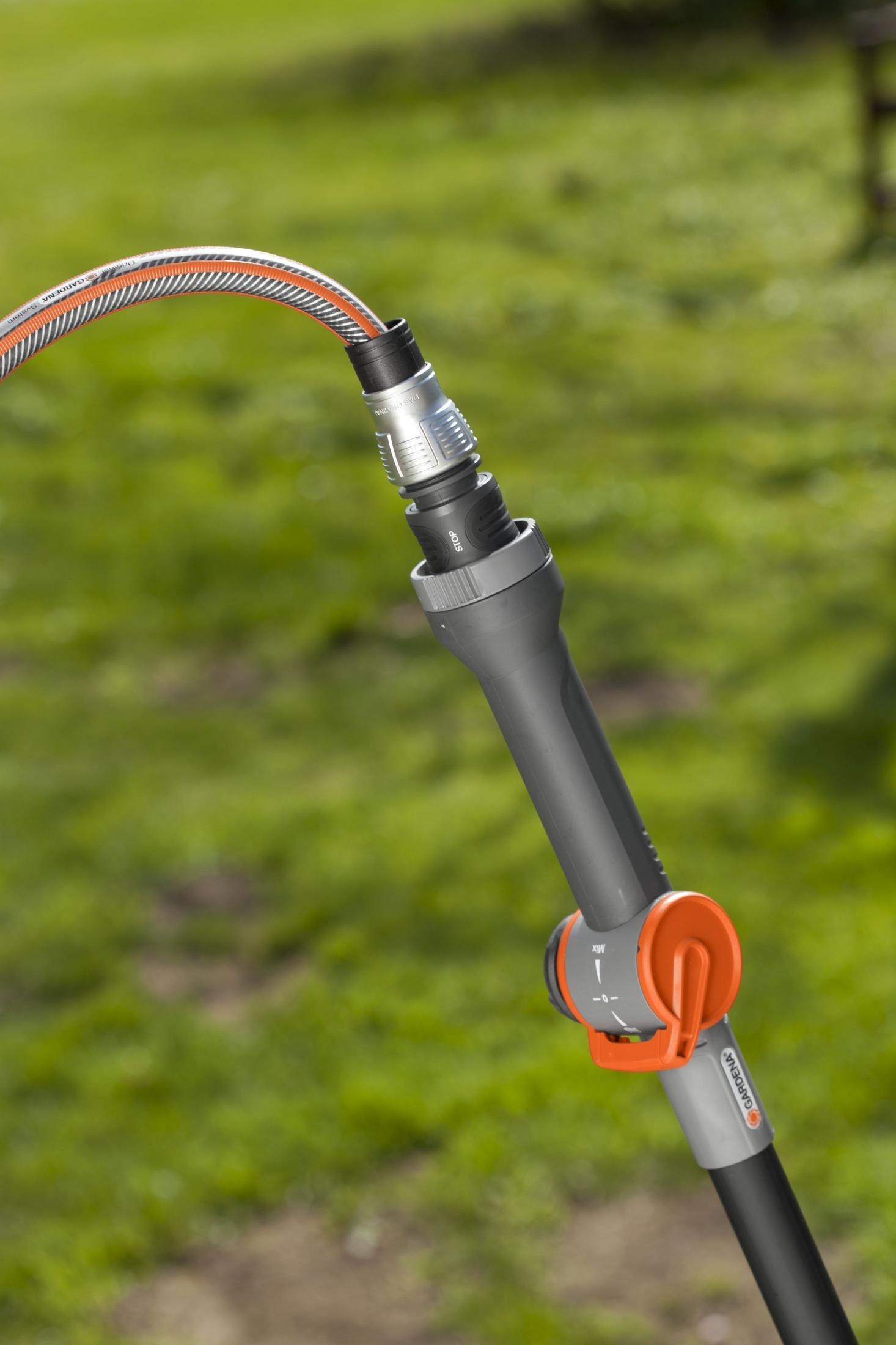 Un tubo da giardino è collegato a un ugello grigio e arancione all'esterno.