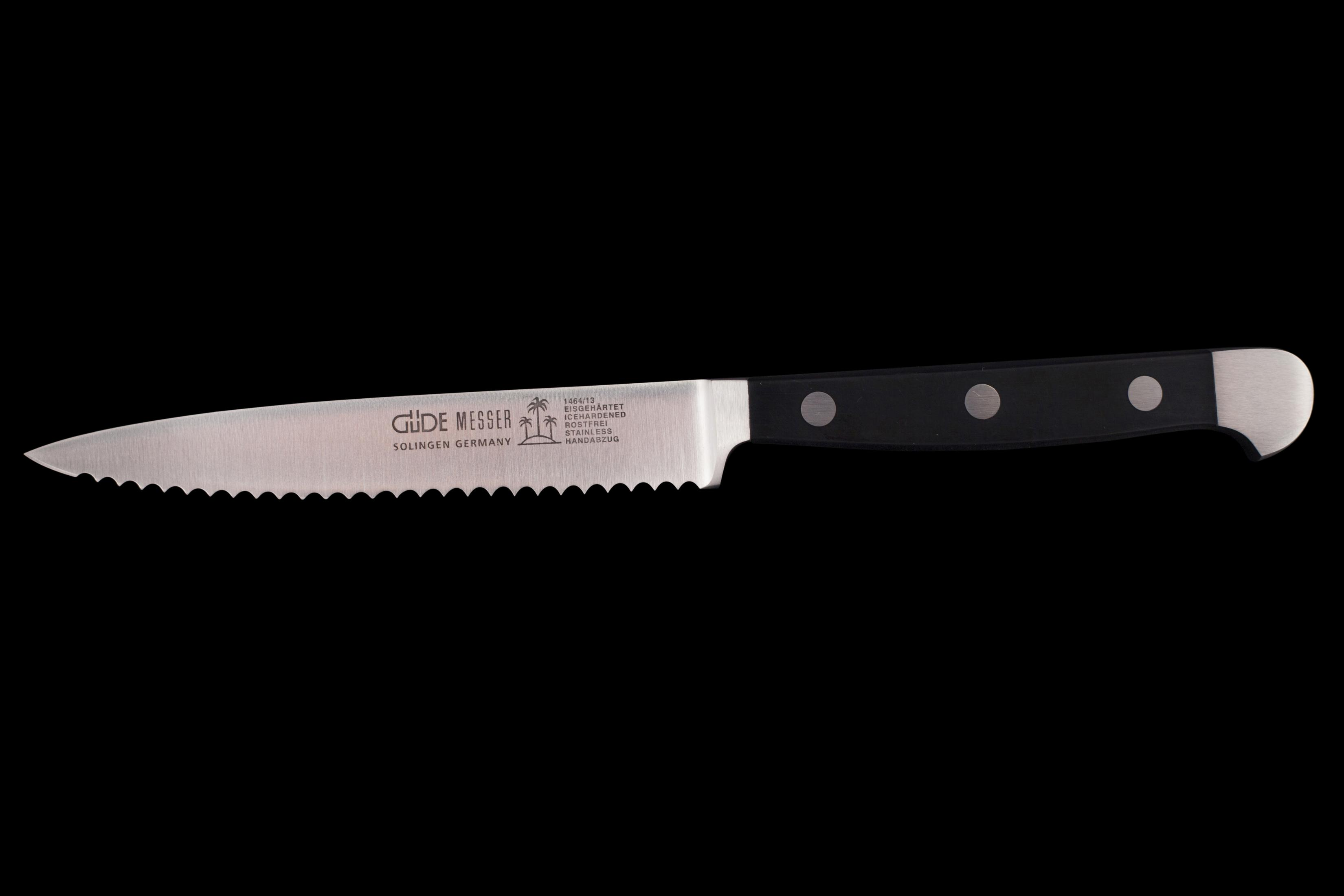 Ein gezahntes Messer mit schwarzem Griff. Die Klinge ist silberfarben und trägt den Namen GÜDE.