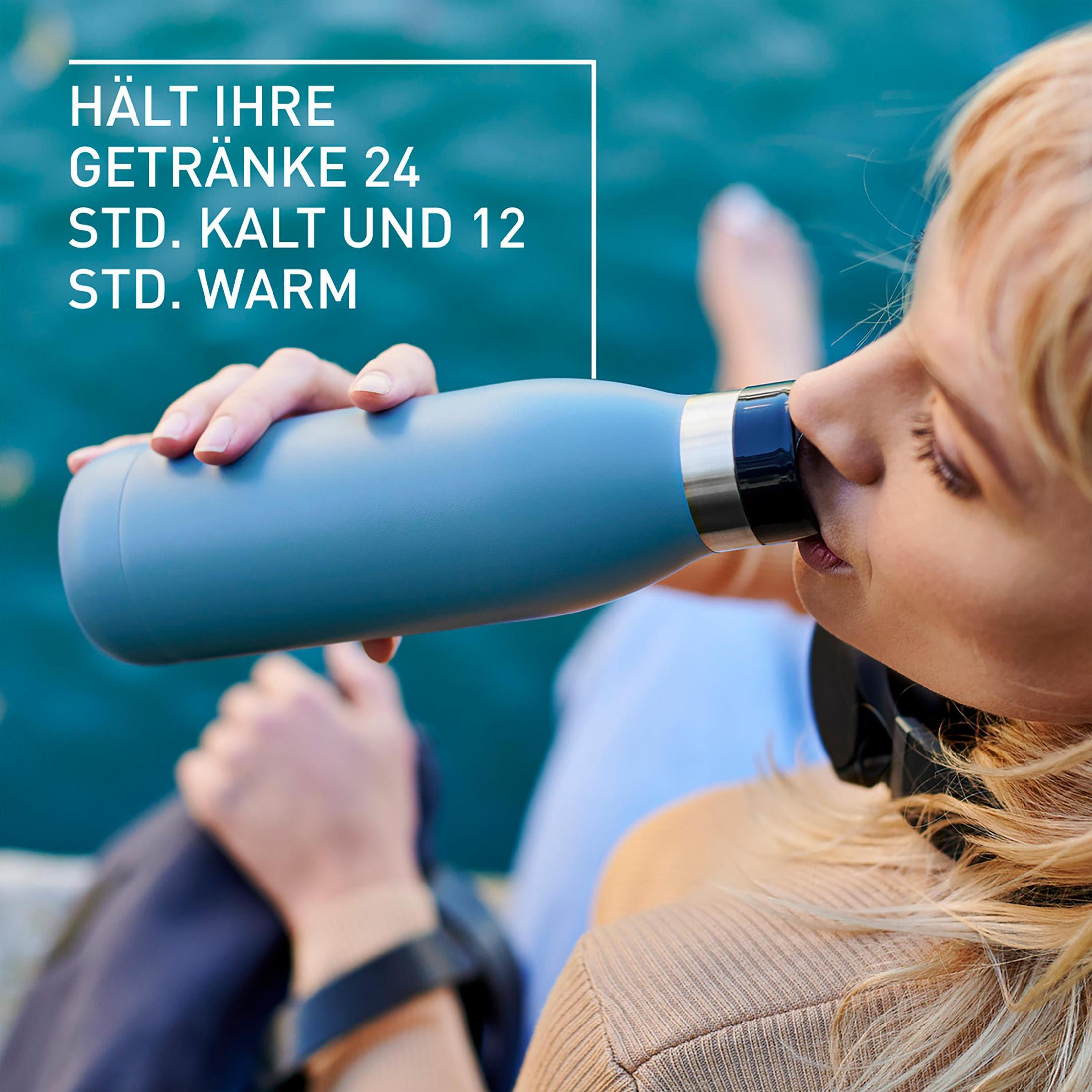 Eine Frau trinkt aus einer blauen Flasche; Text sagt: „HÄLT IHRE GETRÄNKE 24 STD. KALT UND 12 STD. WARM“.