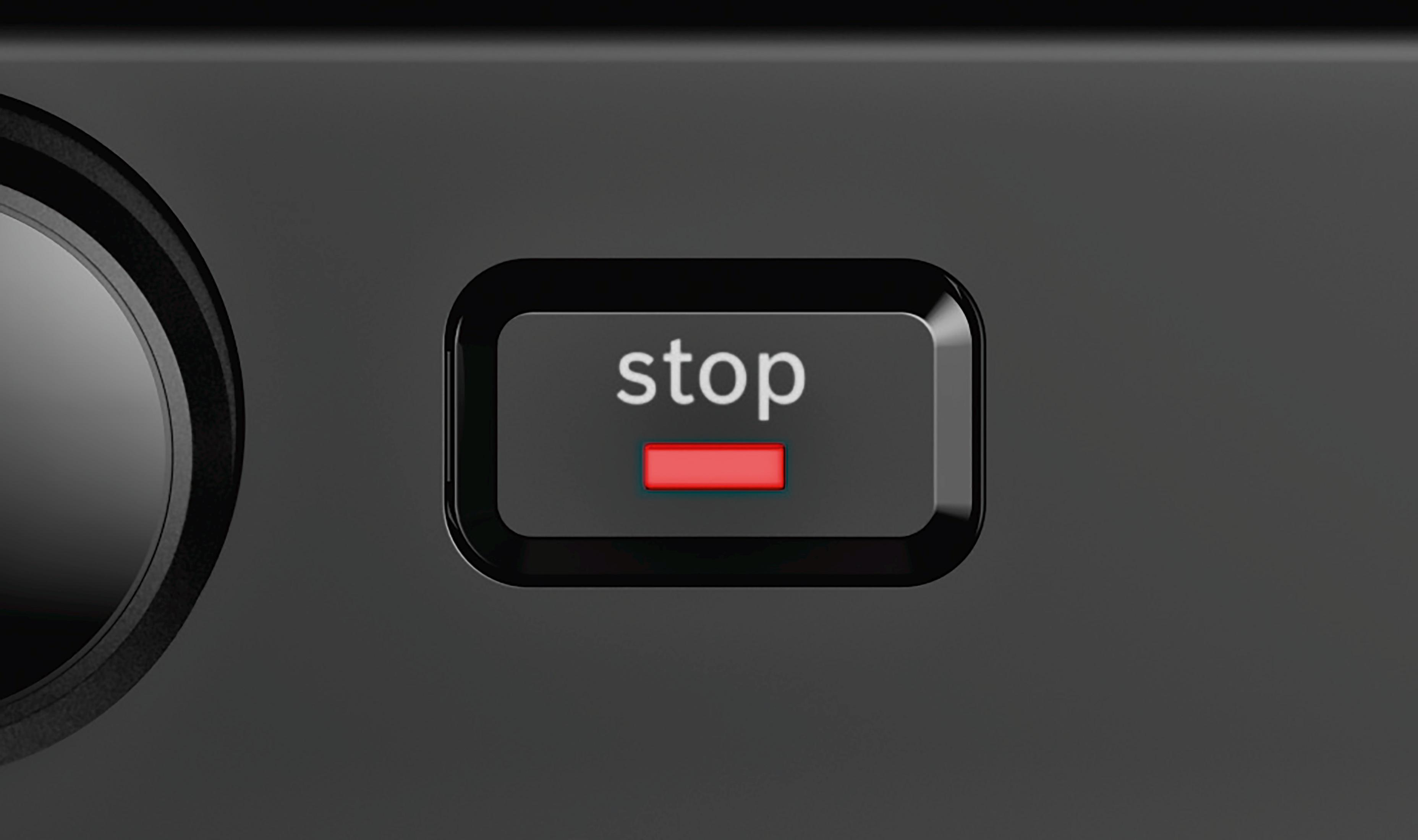 Close-up of the 'stop' button on a black toaster. The button is red when it's on.