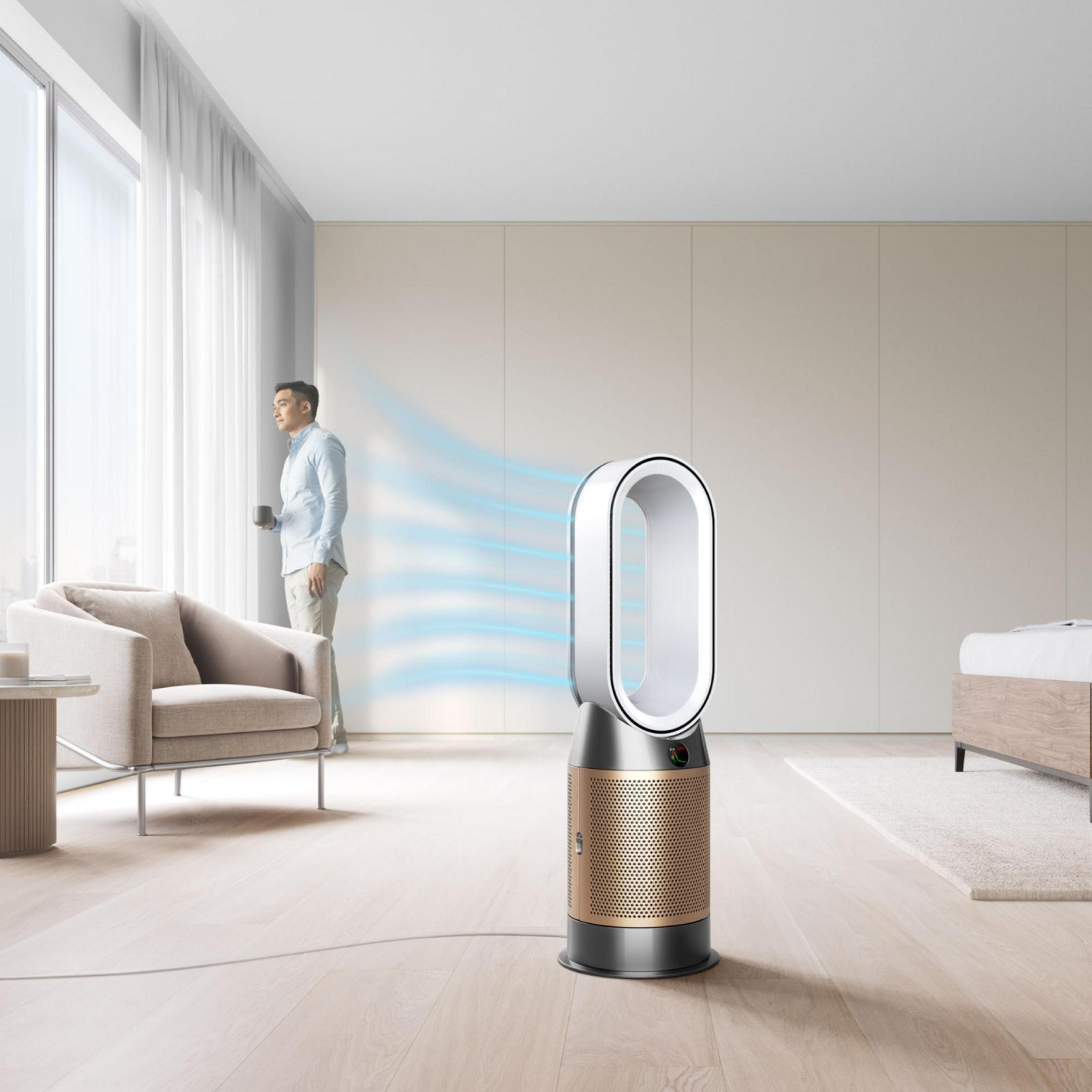 Un uomo guarda fuori dalla finestra, con un purificatore d'aria Dyson in primo piano, in un appartamento moderno.