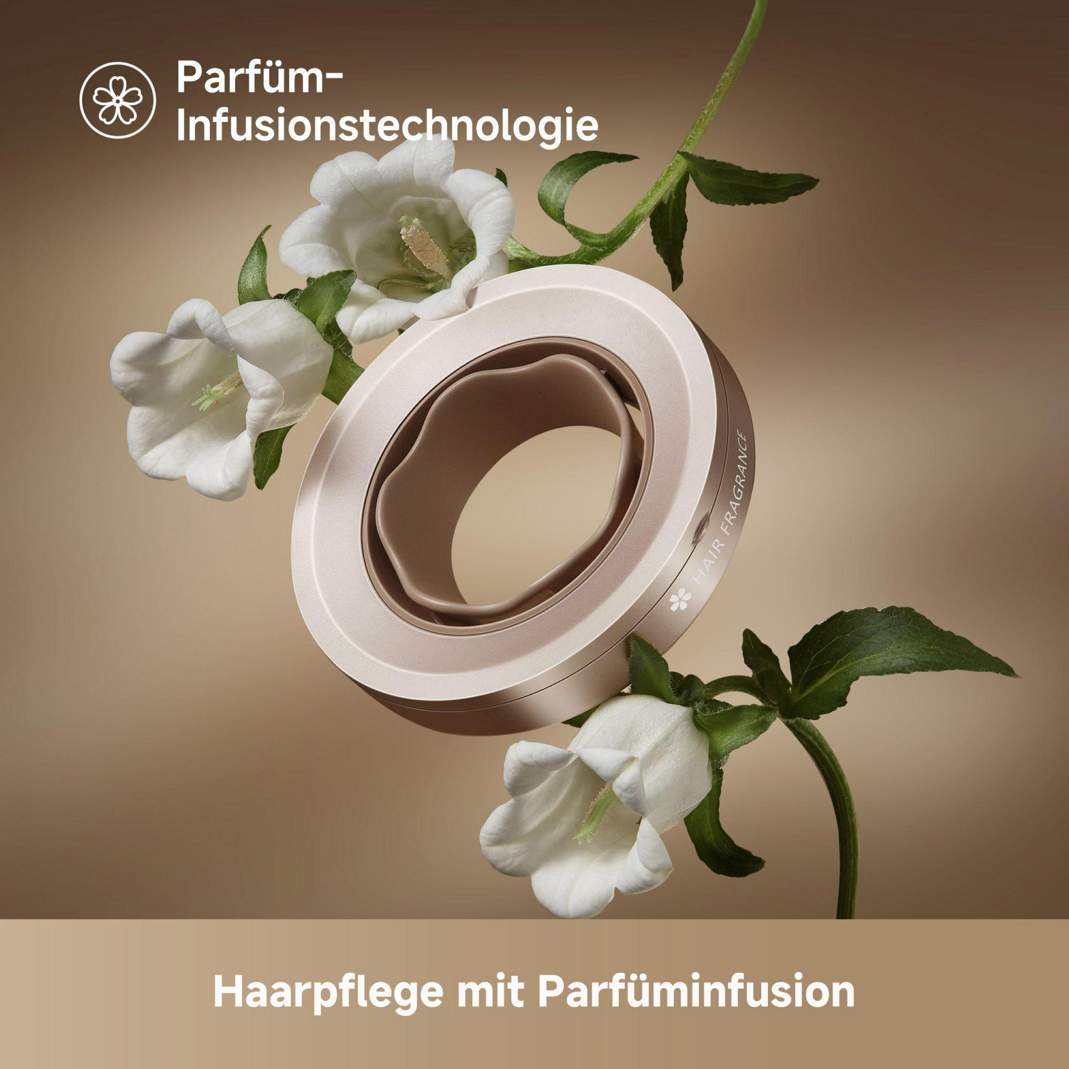 Złota nasadka do suszarki do włosów otoczona białymi kwiatami. Tekst mówi o pielęgnacji włosów z infuzją perfum.
