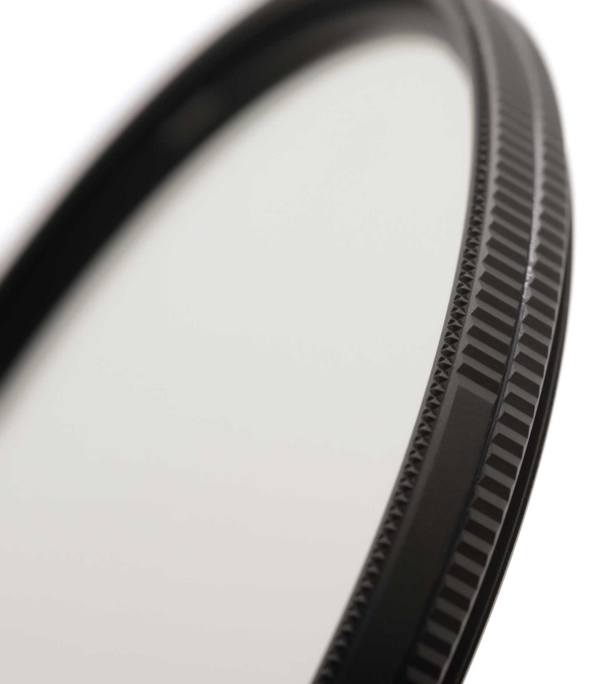 Primo piano di un filtro per obiettivo nero con un bordo ruvido, su sfondo bianco.