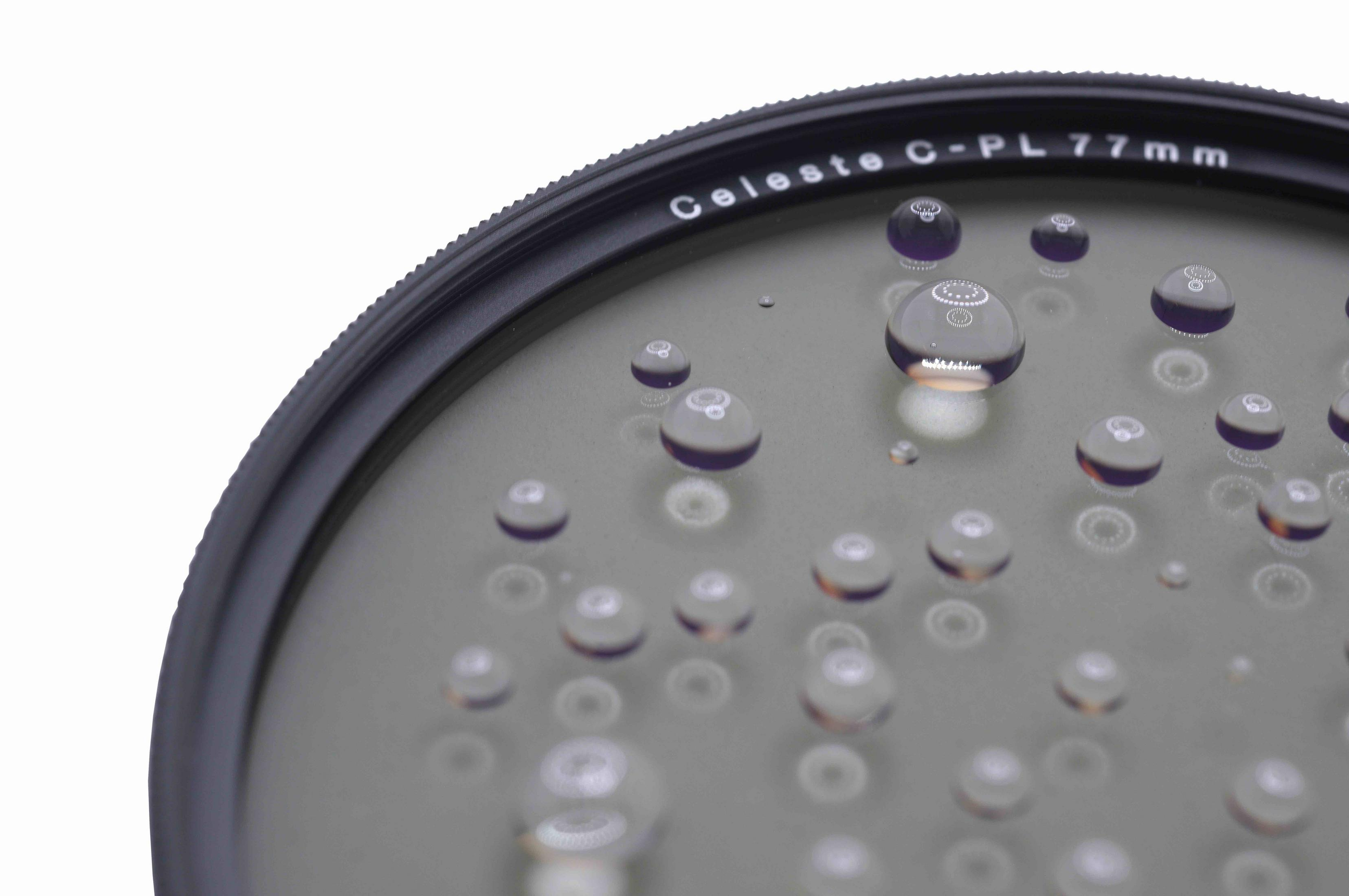 Ein kreisförmiger Objektivfilter mit Wassertropfen darauf. Text 'Celeste C-PL 77mm'. Weißer Hintergrund.