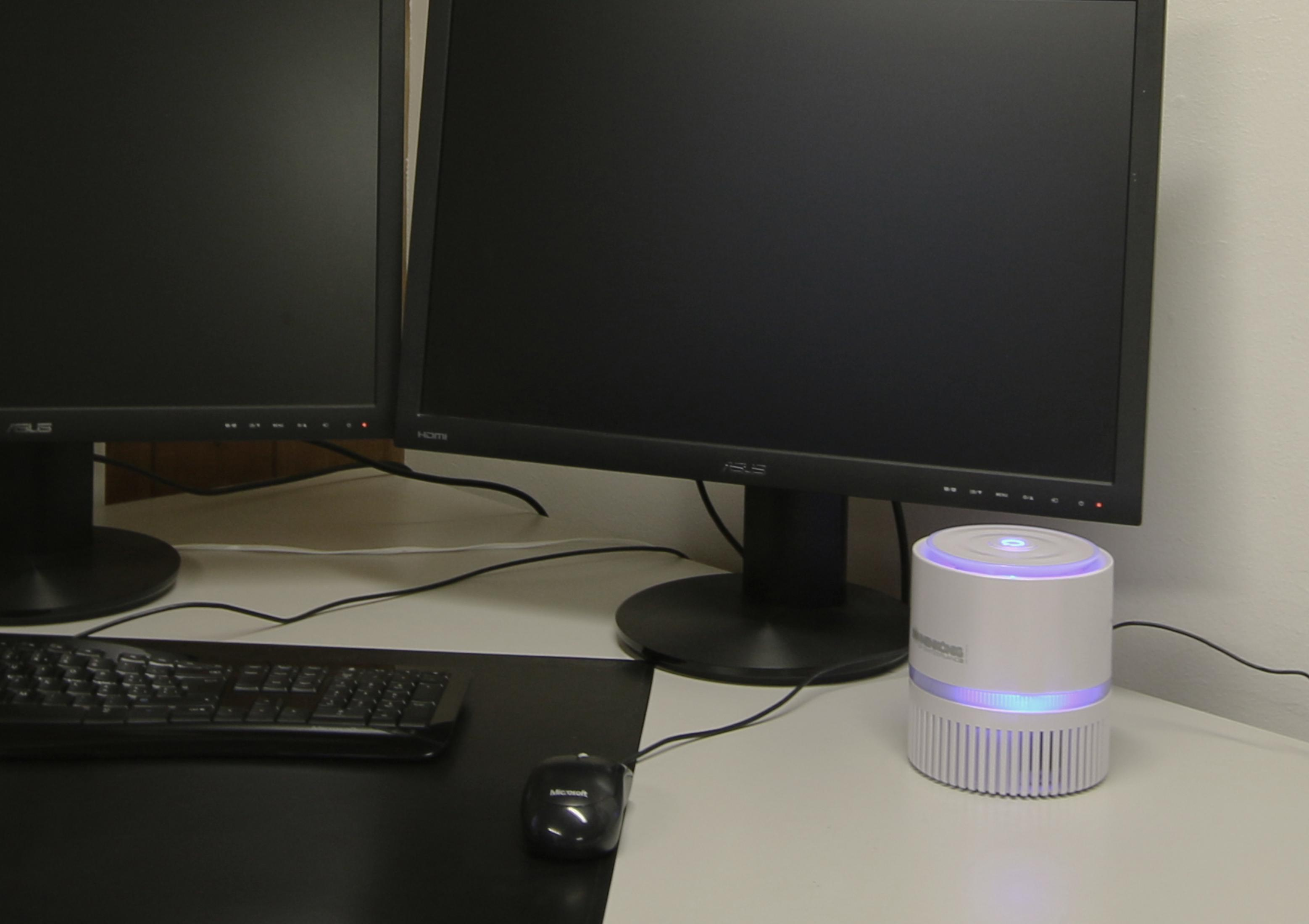 Trappola per zanzare bianca su una scrivania tra due monitor, tastiera e mouse.