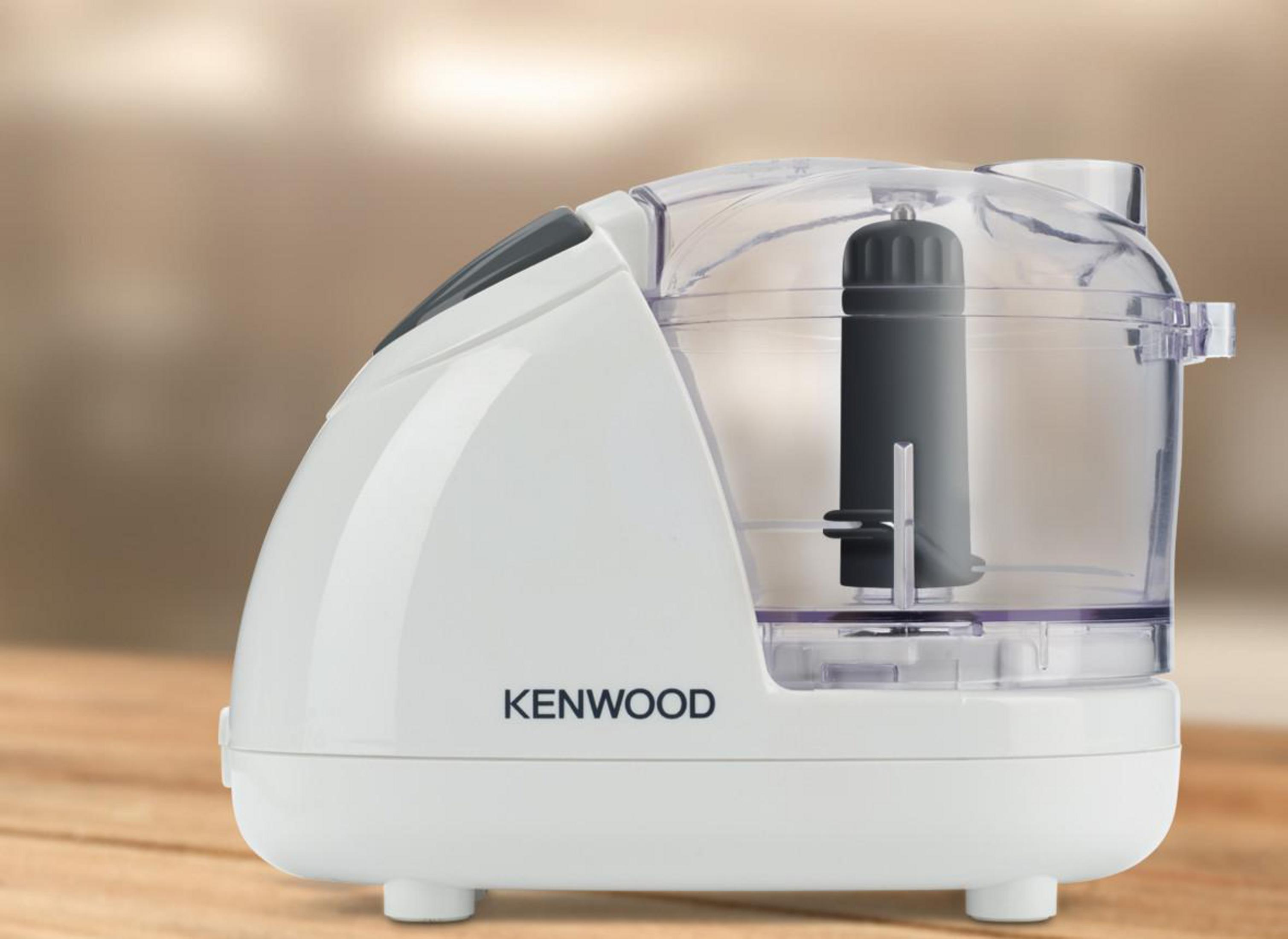 Ein weißer Kenwood-Foodprozessor auf einer Holzoberfläche. Er hat eine transparente Schüssel und eine schwarze Klinge.
