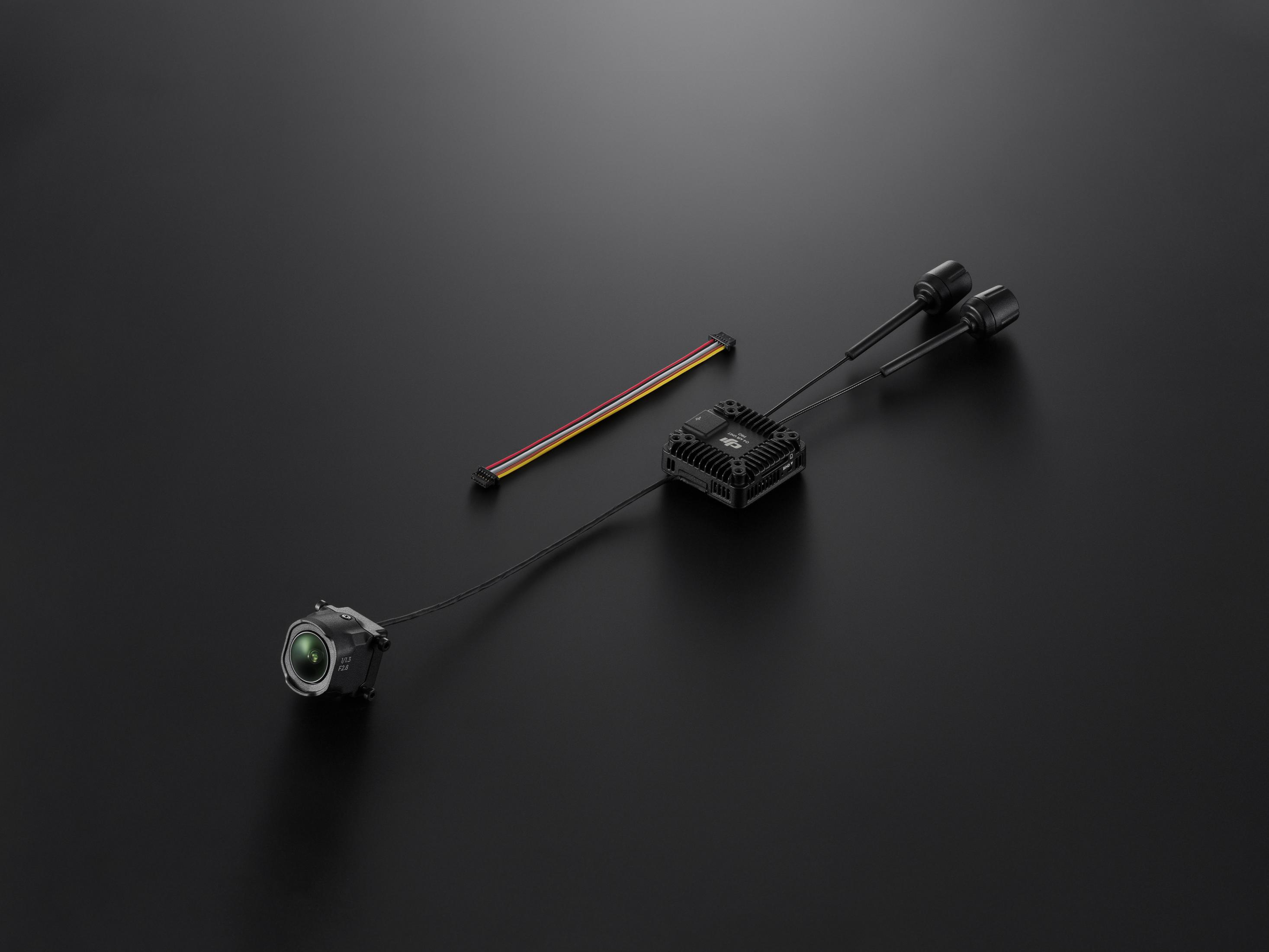 Componenti neri di un drone su sfondo nero. Include una fotocamera, un modulo e due antenne.