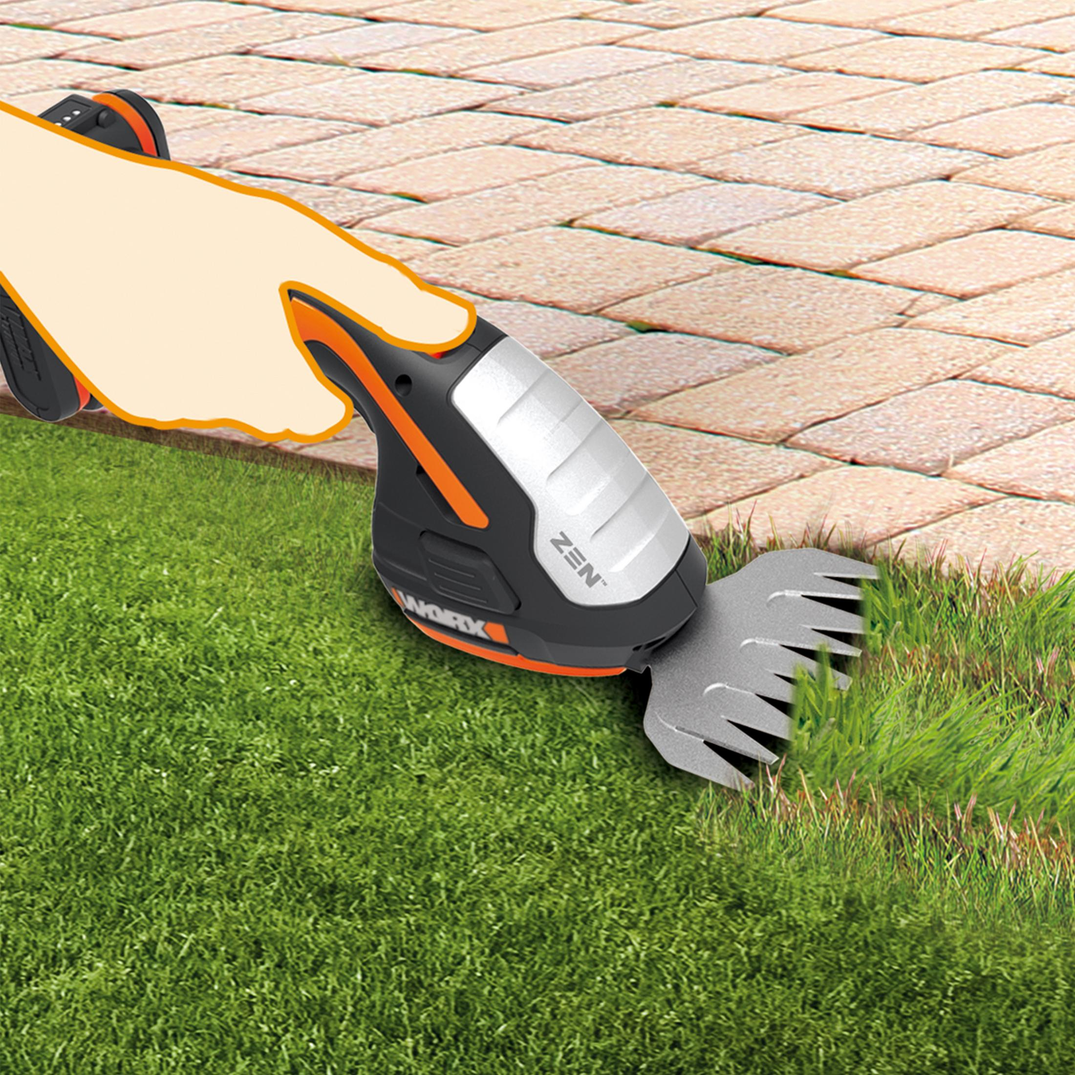 Ein WORX-Grastrimmer, der Gras neben einem Steinpfad schneidet.
