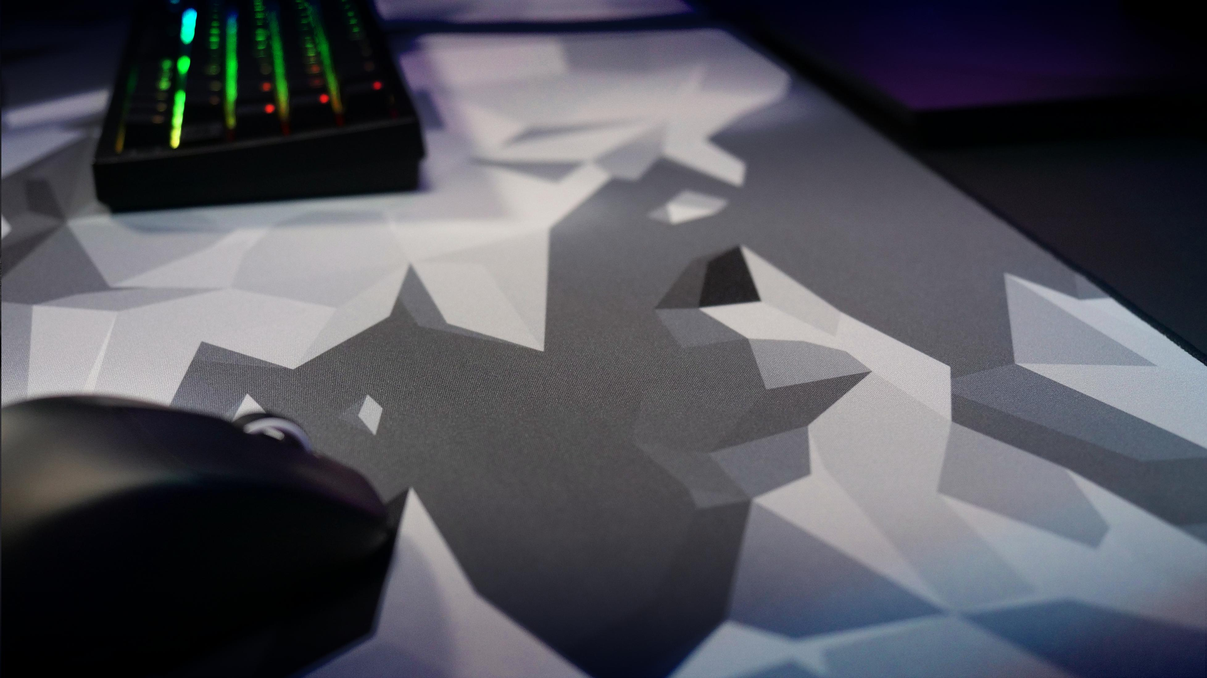 Nahaufnahme eines Mauspads mit geometrischem Muster, einer Tastatur und einer Maus.