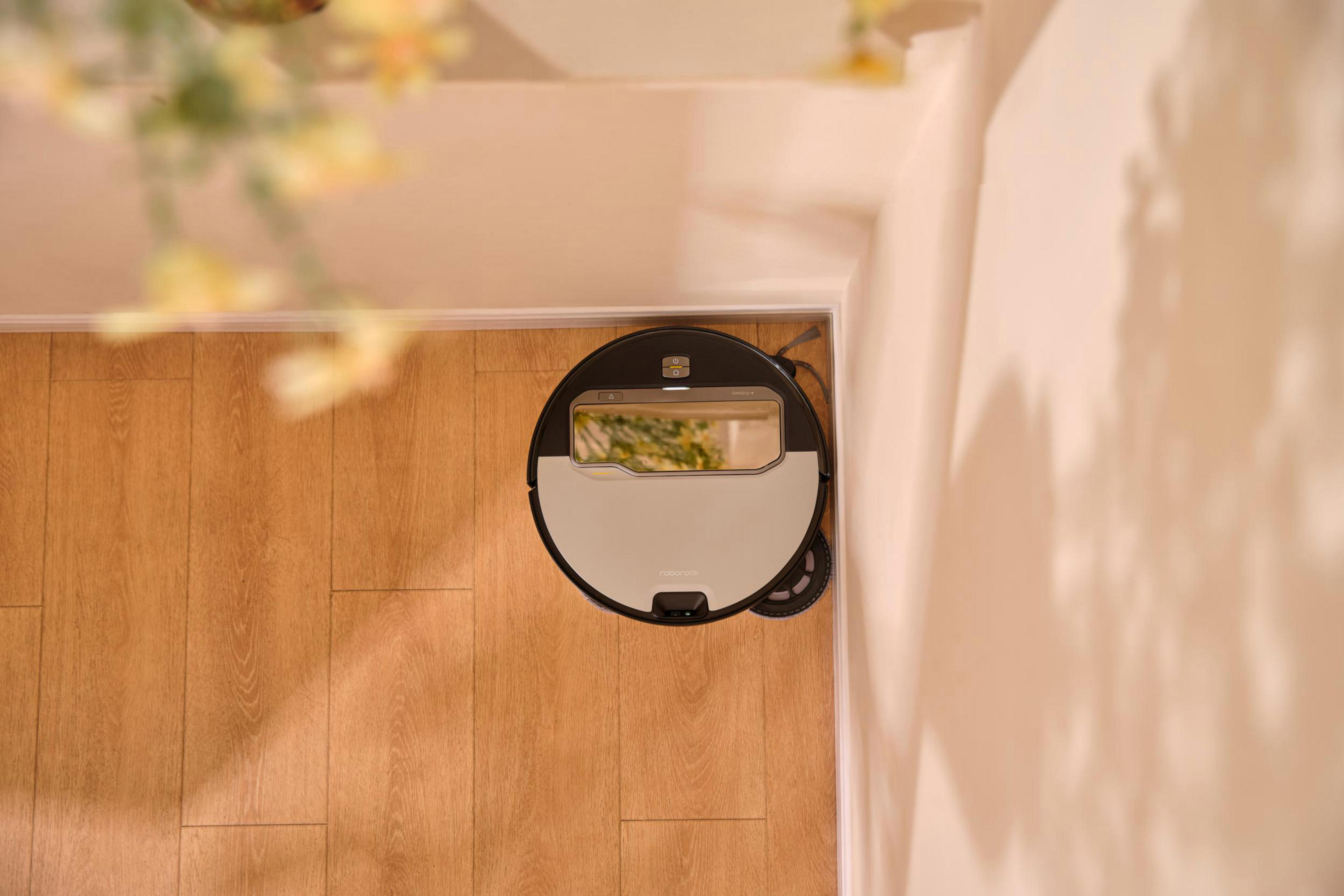 Ein Roboter-Staubsauger auf einem Holzboden, von oben aufgenommen.