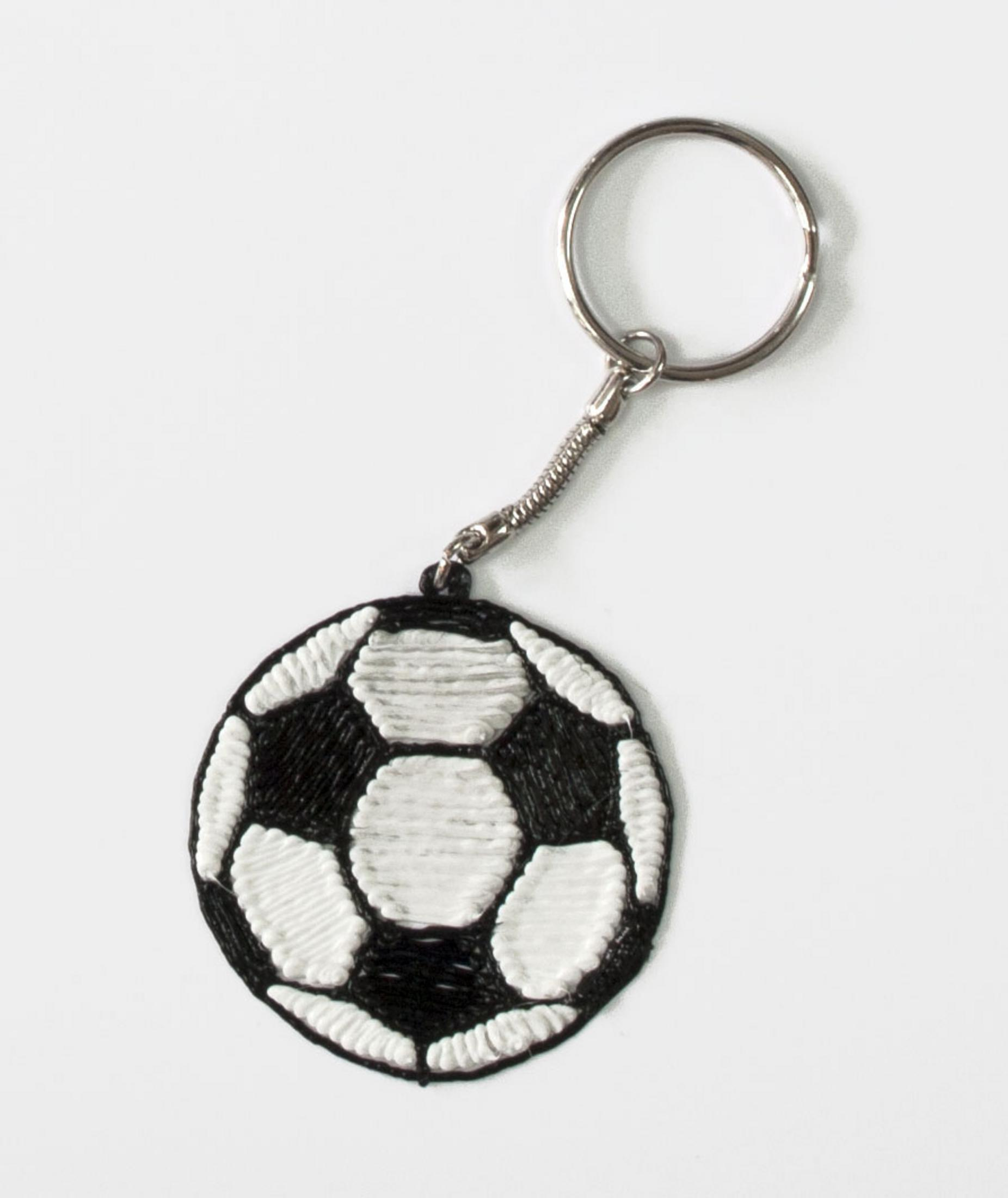 Un portachiavi a forma di pallone da calcio con pentagoni bianchi e neri, con anello metallico.