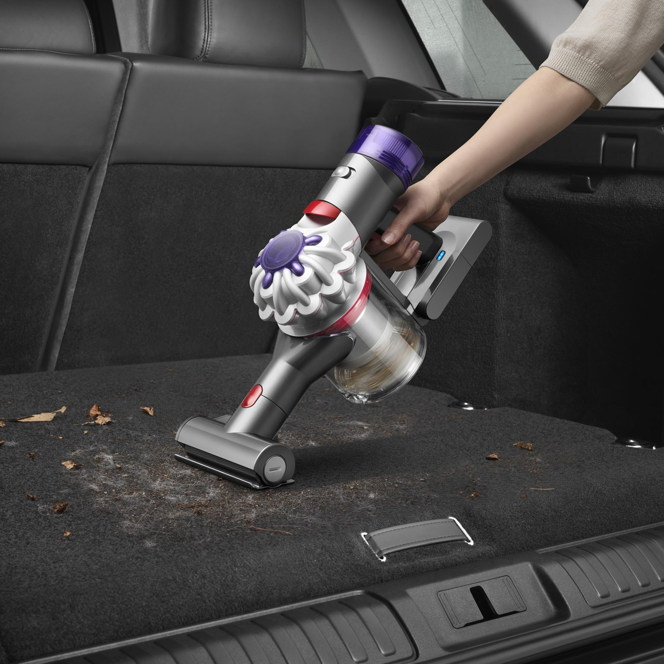 Eine Person saugt einen Kofferraum mit einem Dyson Akku-Staubsauger.