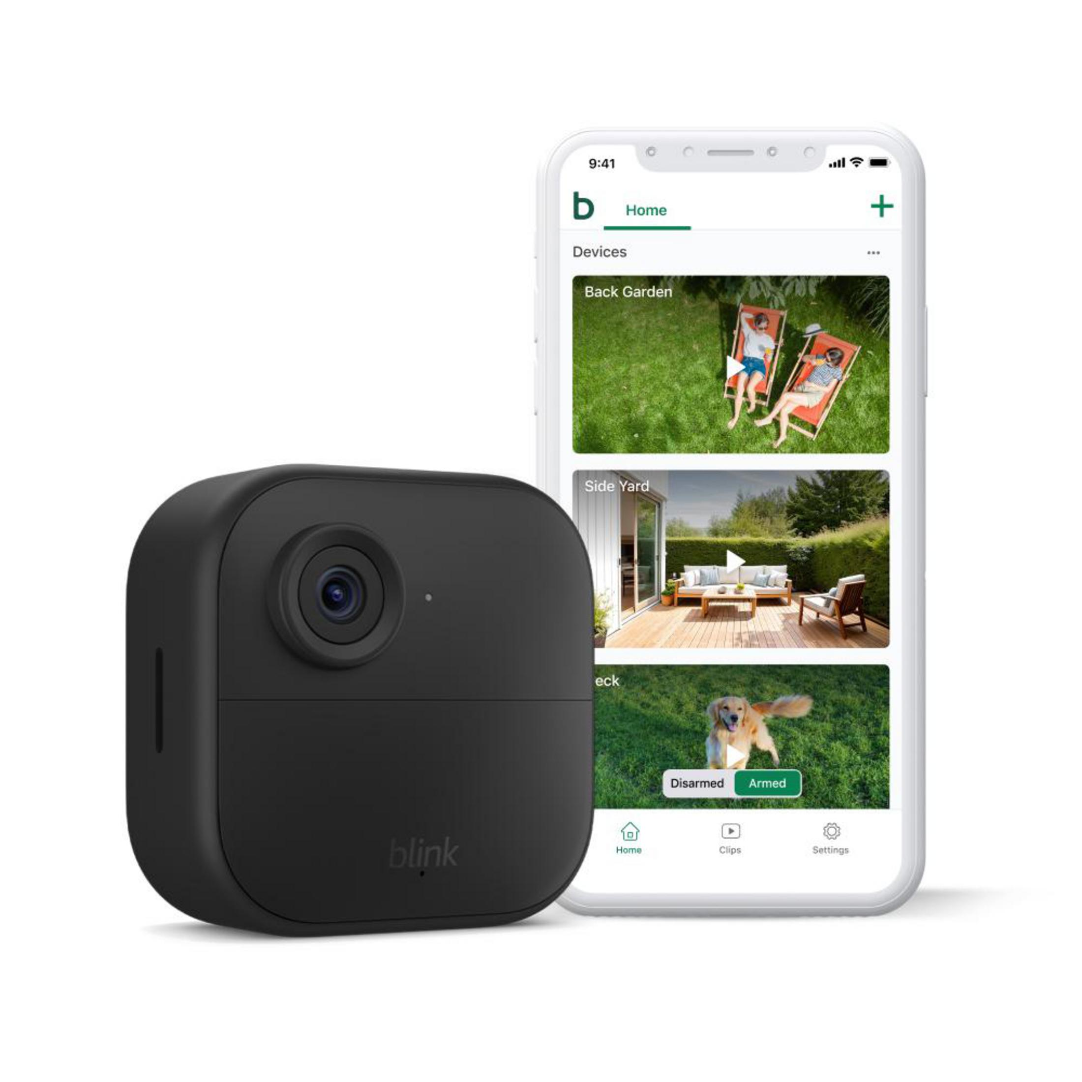 Una telecamera di sicurezza nera e un telefono che mostra l'app di sicurezza. L'app mostra una scena del cortile. Sfondo bianco.