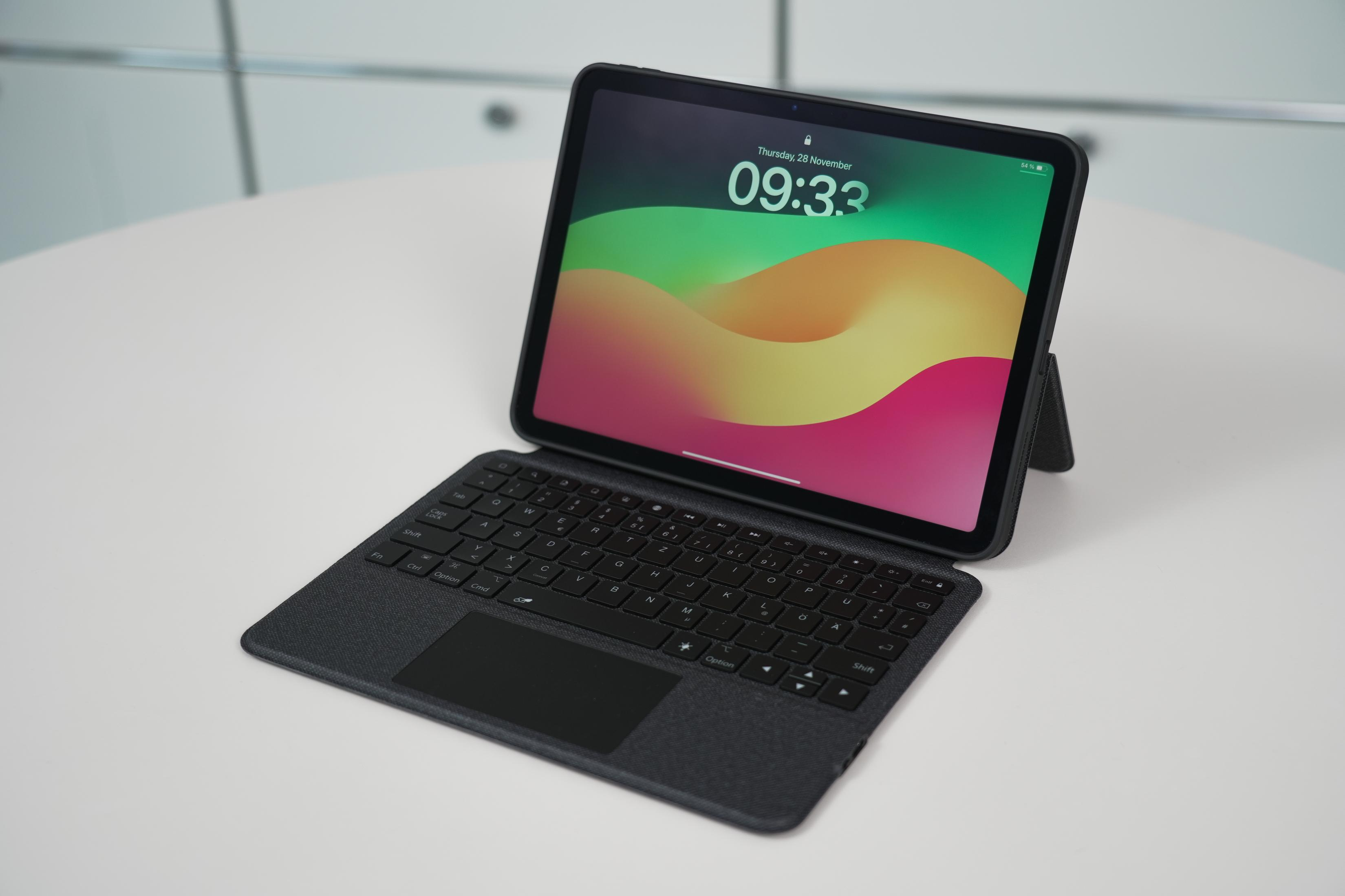 Ein iPad mit Tastaturhülle liegt auf einem weißen Tisch. Der Bildschirm zeigt die Uhrzeit 09:33 an.