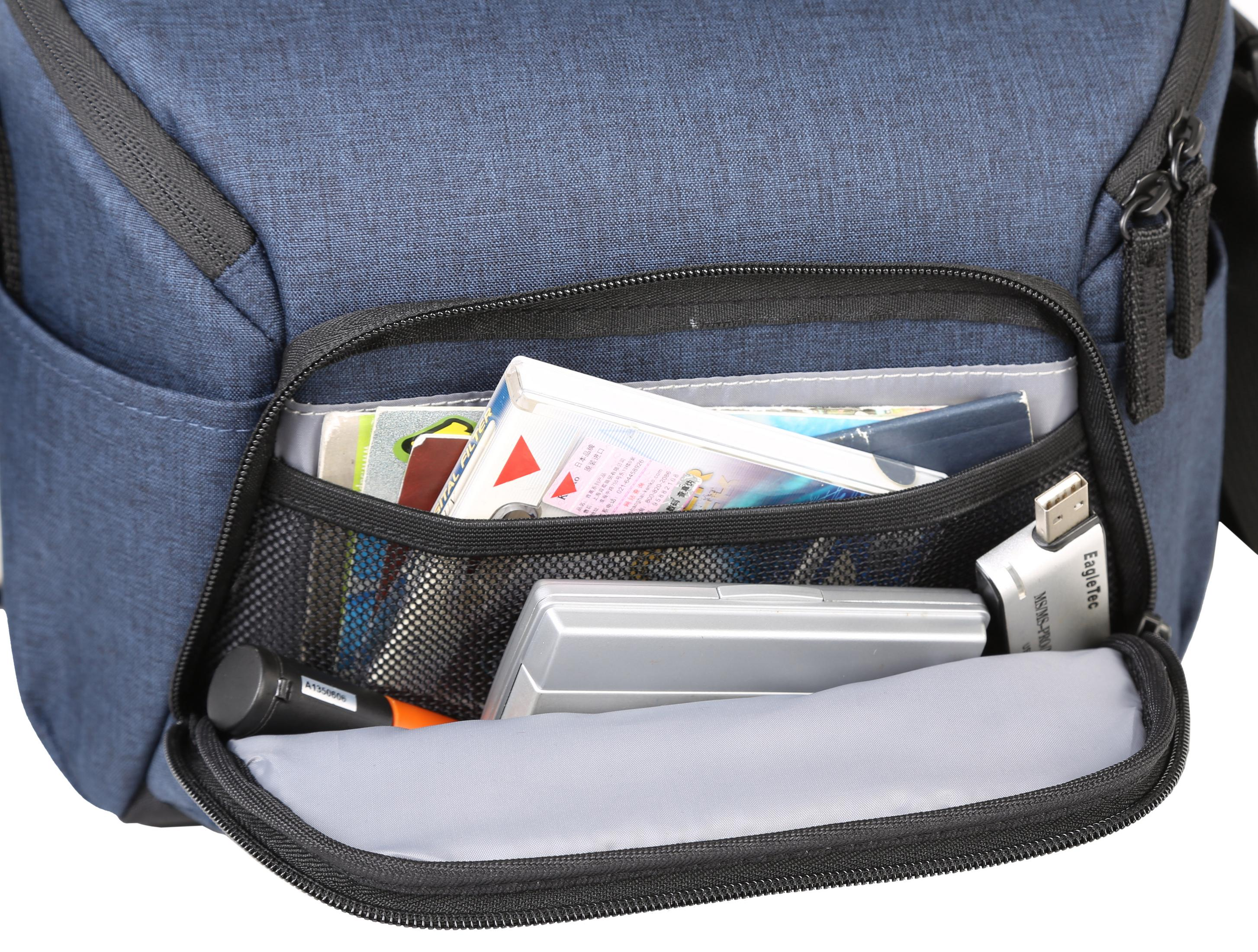 Bolsa de cámara azul abierta, mostrando bolsillos con libros, accesorios y una unidad USB.