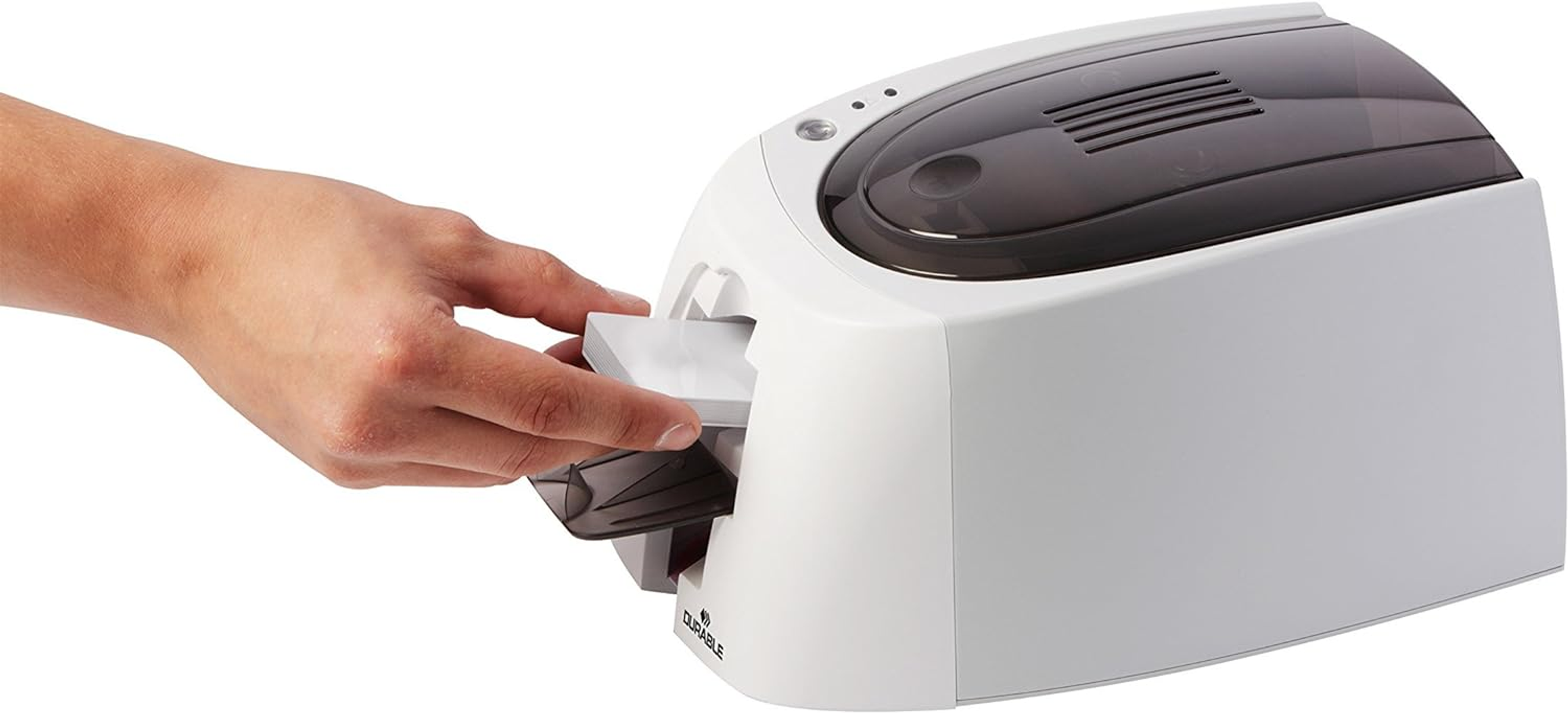 Una mano inserisce una scheda in una stampante per carte bianca su sfondo bianco.