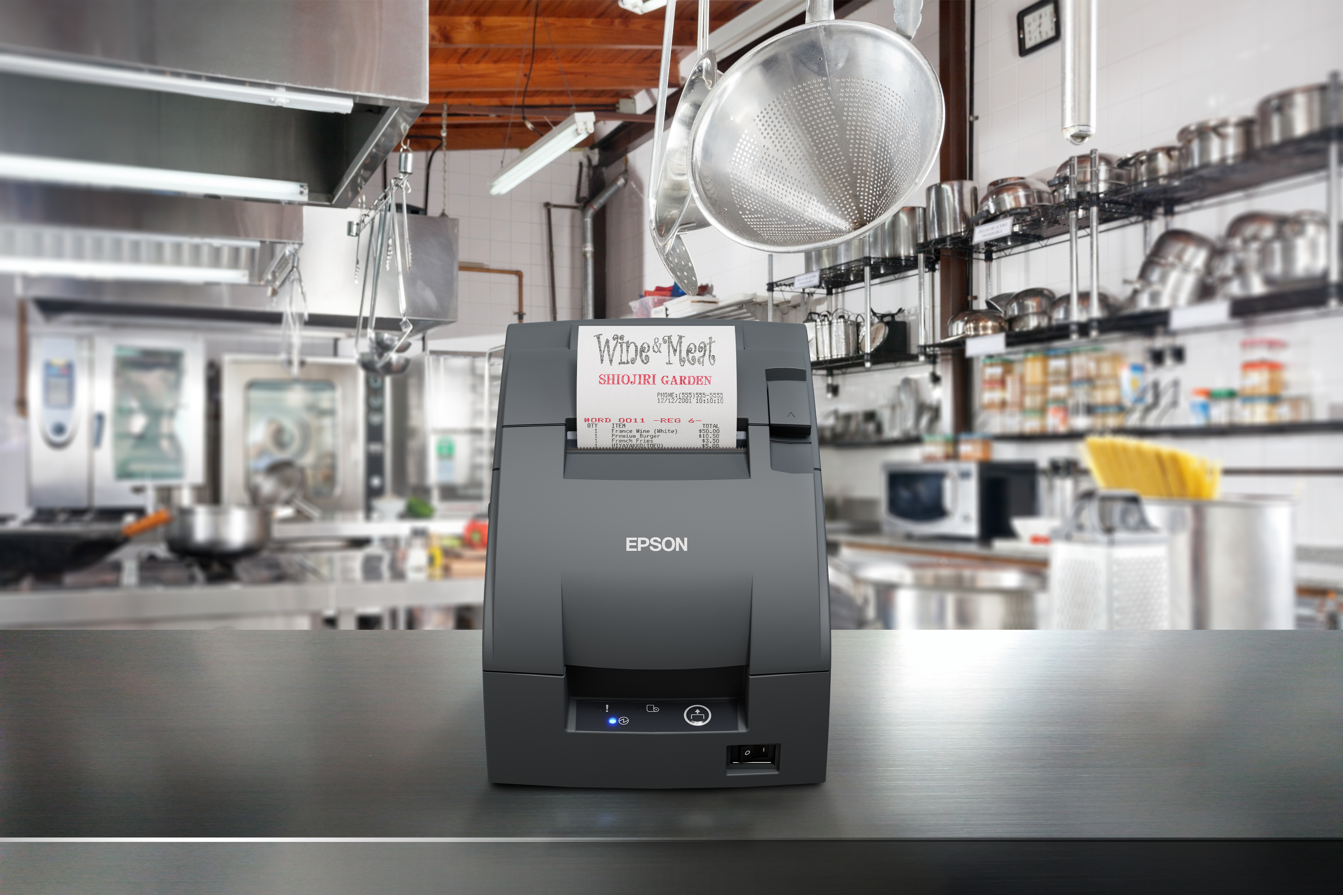 Stampante Epson su un tavolo di metallo in una cucina commerciale, con attrezzature in acciaio inossidabile sullo sfondo.