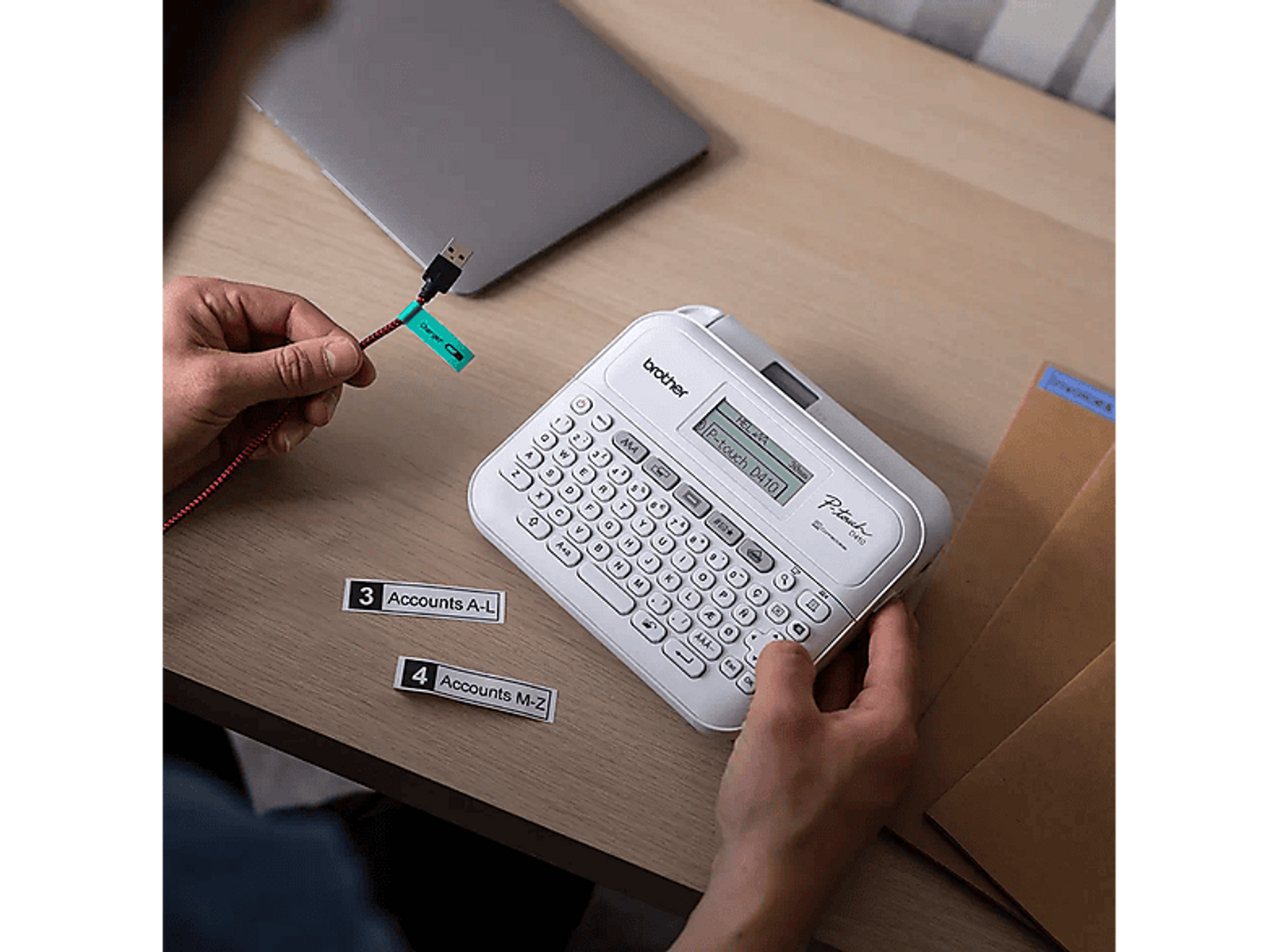 Mani che usano un'etichettatrice per etichettare un cavo USB. Etichette e un laptop sono su una scrivania di legno.