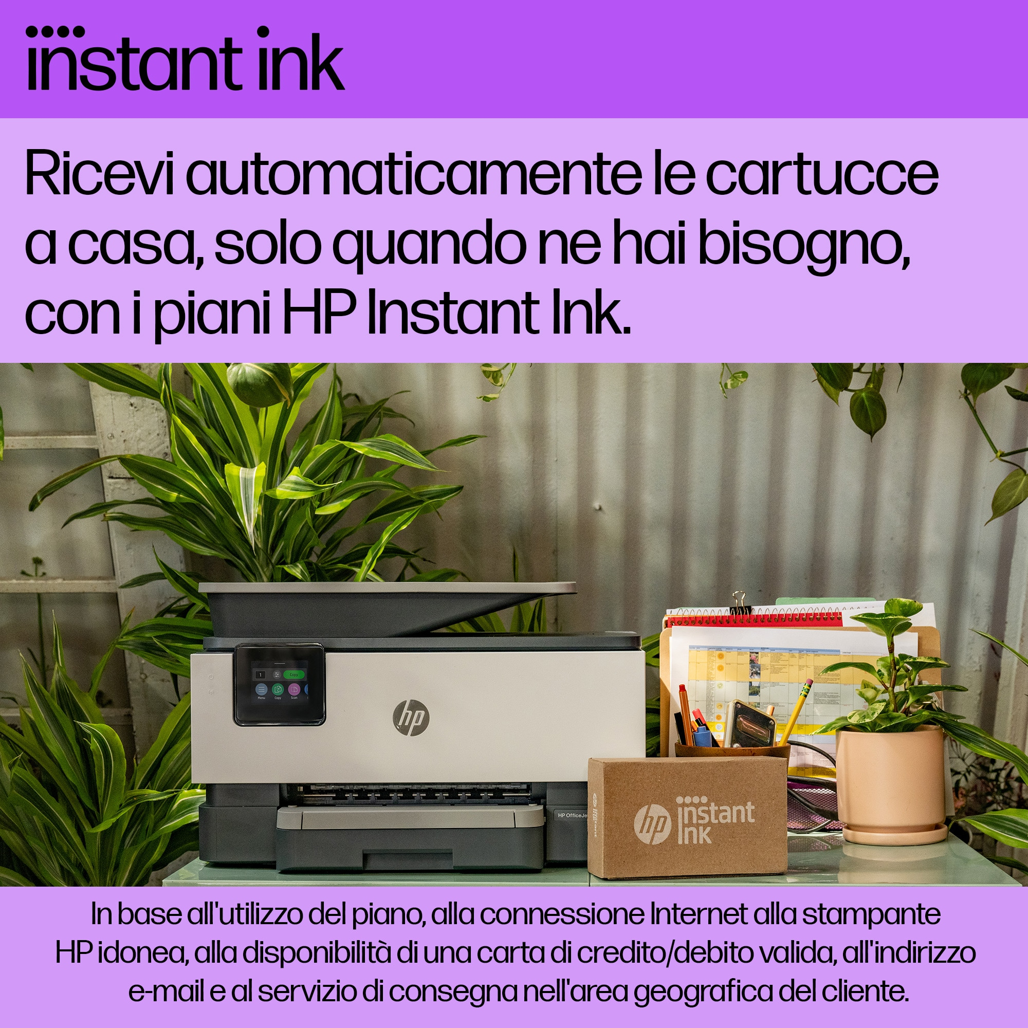 Stampante con scatola Instant Ink su un tavolo di vetro circondato da piante e un calendario.