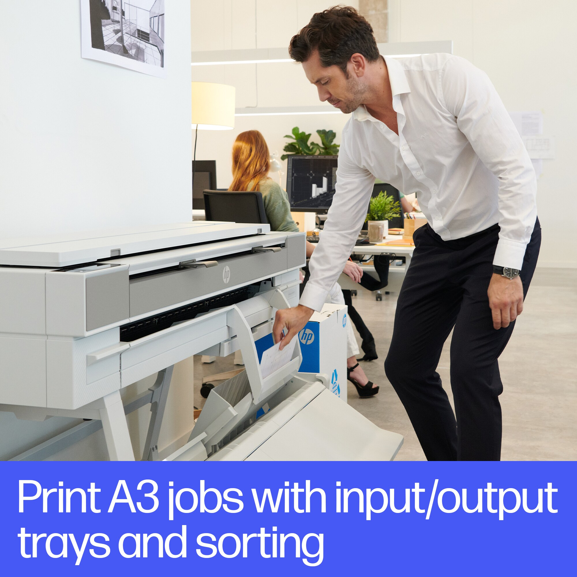 Een man laadt een plotter. De tekst zegt: 'Print A3-jobs met input/output trays en sortering'.