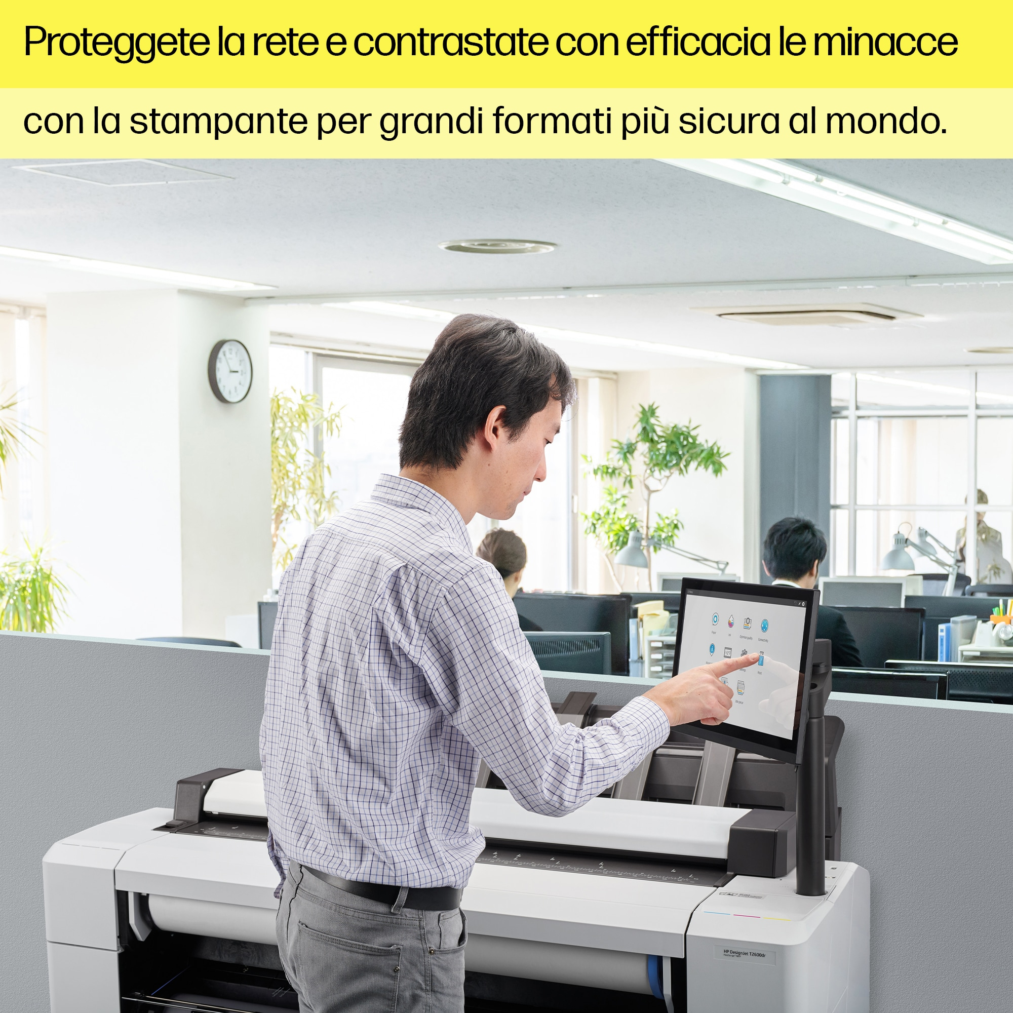 Obraz przedstawia białą drukarkę HP DesignJet T850 w biurze z osobą korzystającą w pobliżu z tabletu.