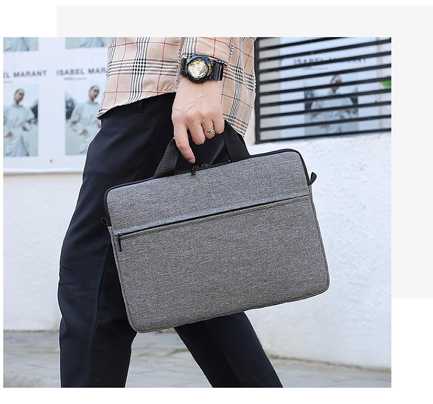Eine Person in schwarzen Hosen trägt eine graue Laptoptasche an den Griffen im Freien.