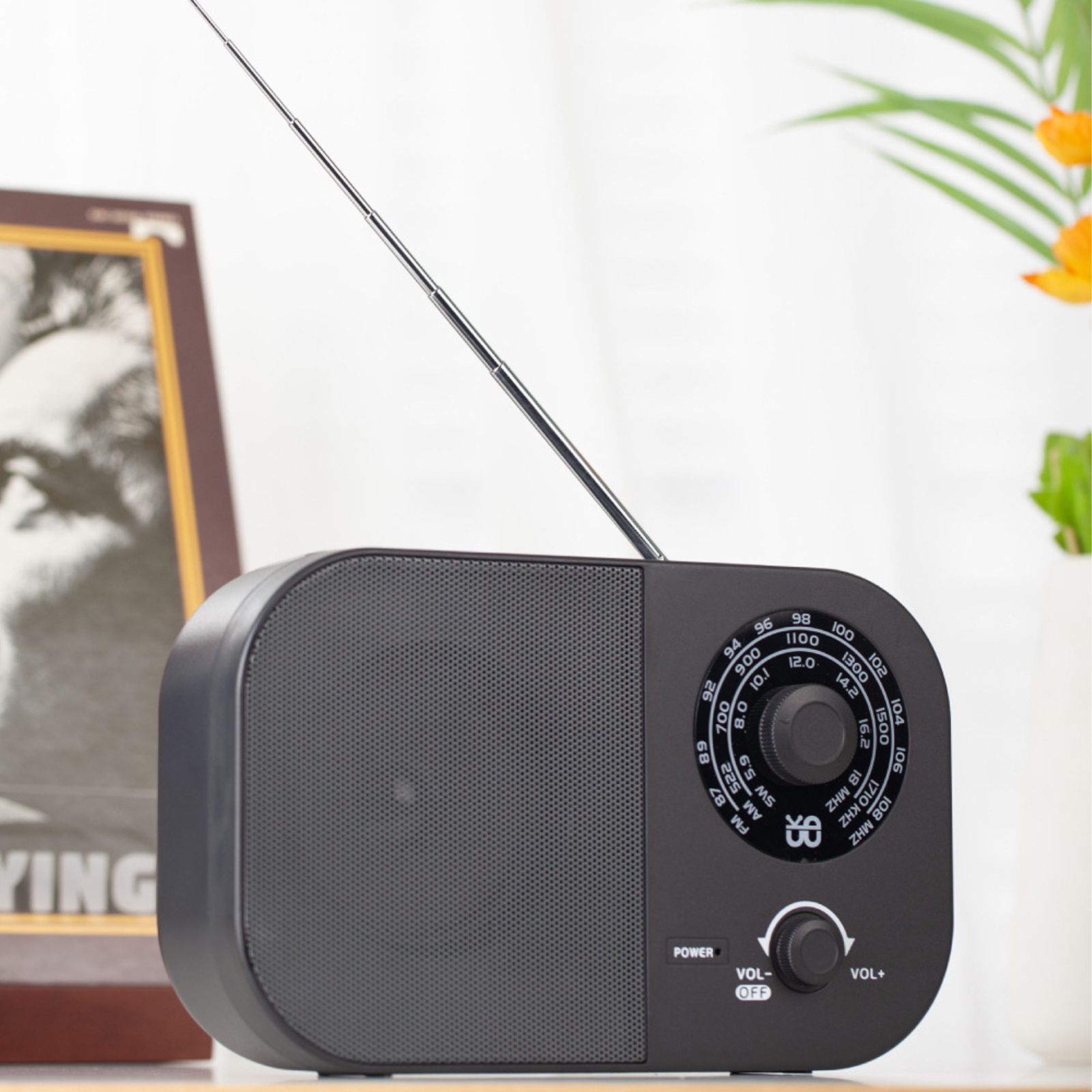 Schwarzes Radio mit einem Lautsprecher auf der linken Seite, einem Abstimmungsrad und einer Ein-/Aus- und Lautstärkeregelung.