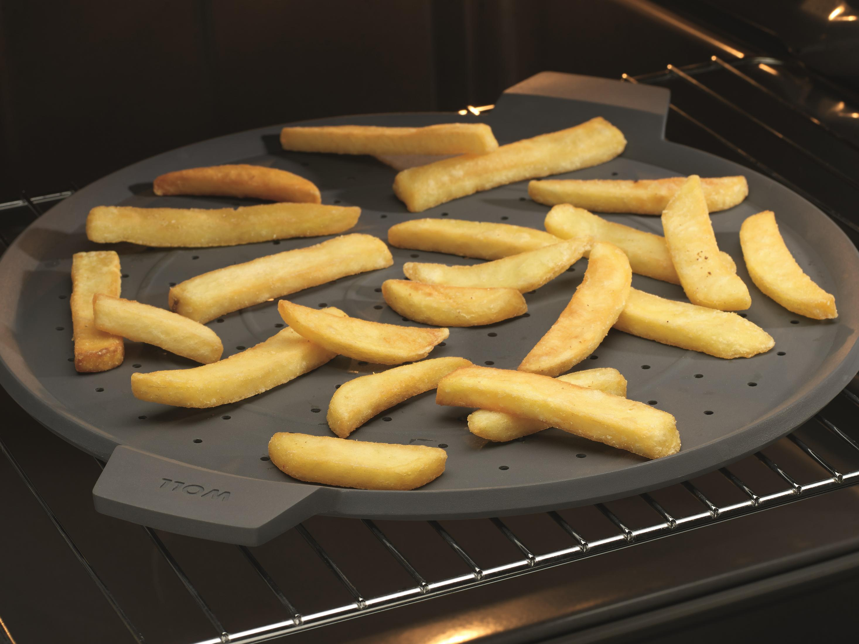 Pommes Frites, die auf einem grauen Silikon-Spritzschutz in einem Ofen kochen.