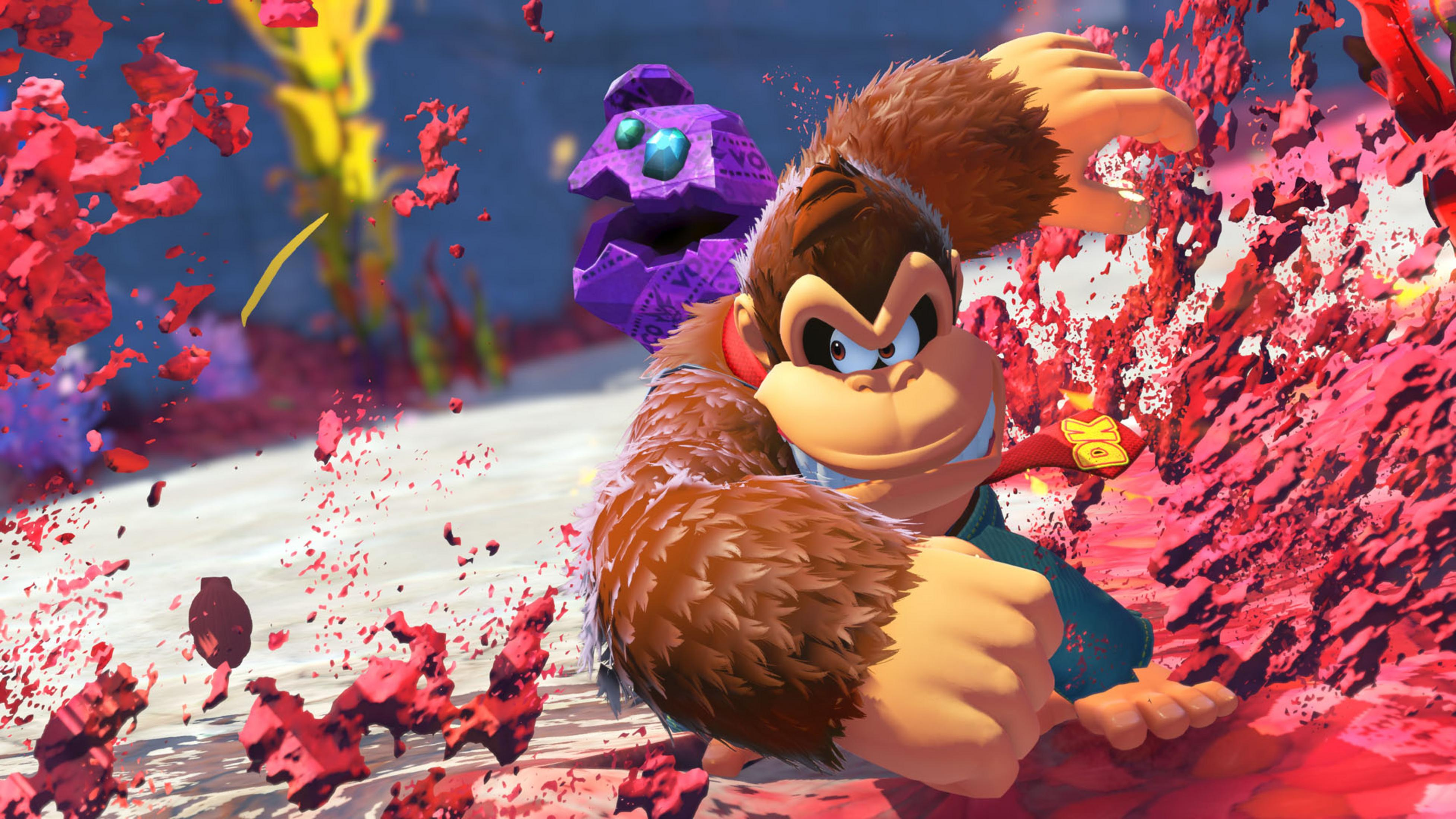 Donkey Kong z determinowanym wyrazem twarzy, trzymający fioletowy przedmiot, otoczony czerwonymi cząsteczkami.