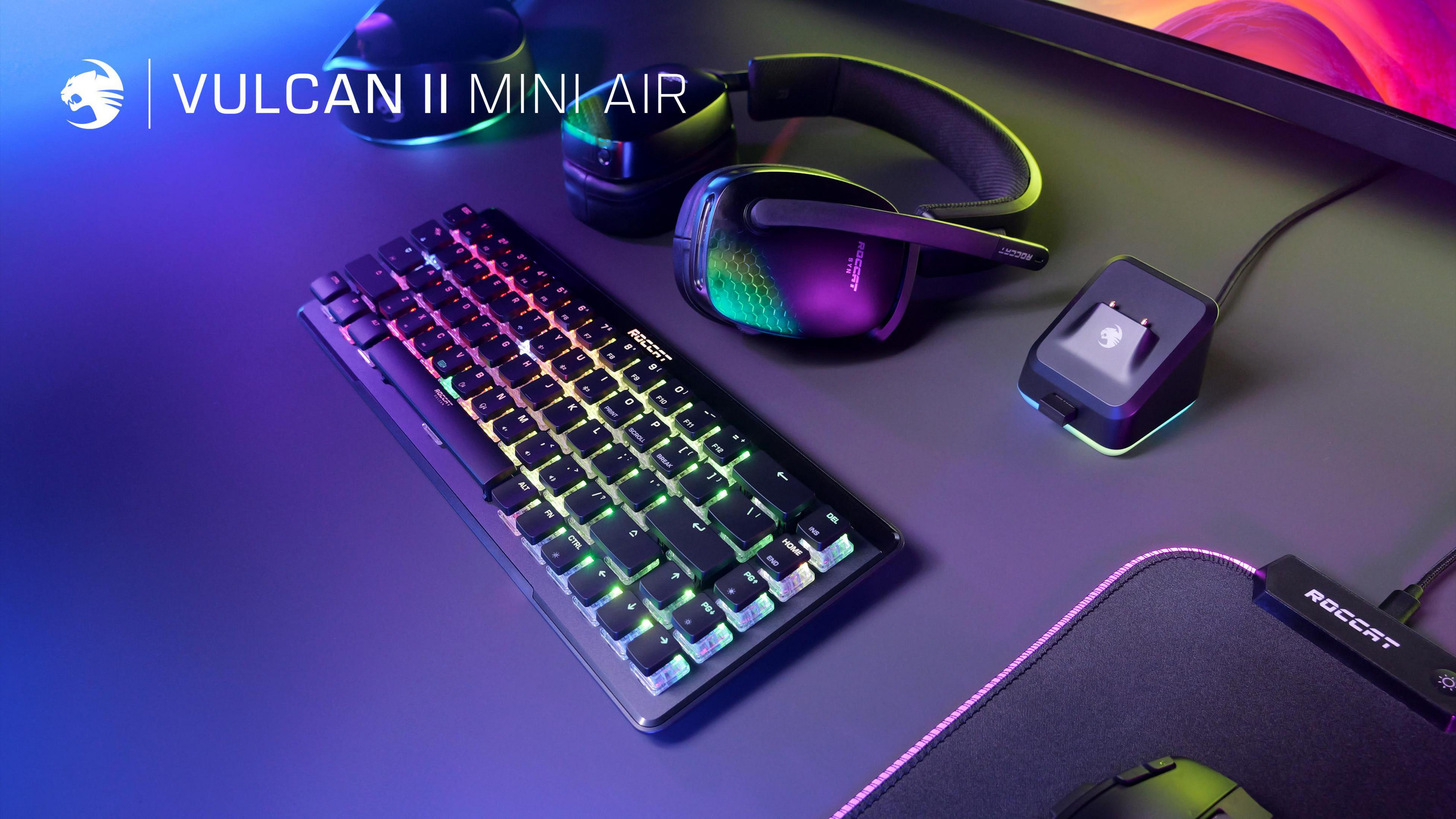 Roccat Vulcan II Mini Air Tastatur mit Headset und Ladestation auf einem Schreibtisch.
