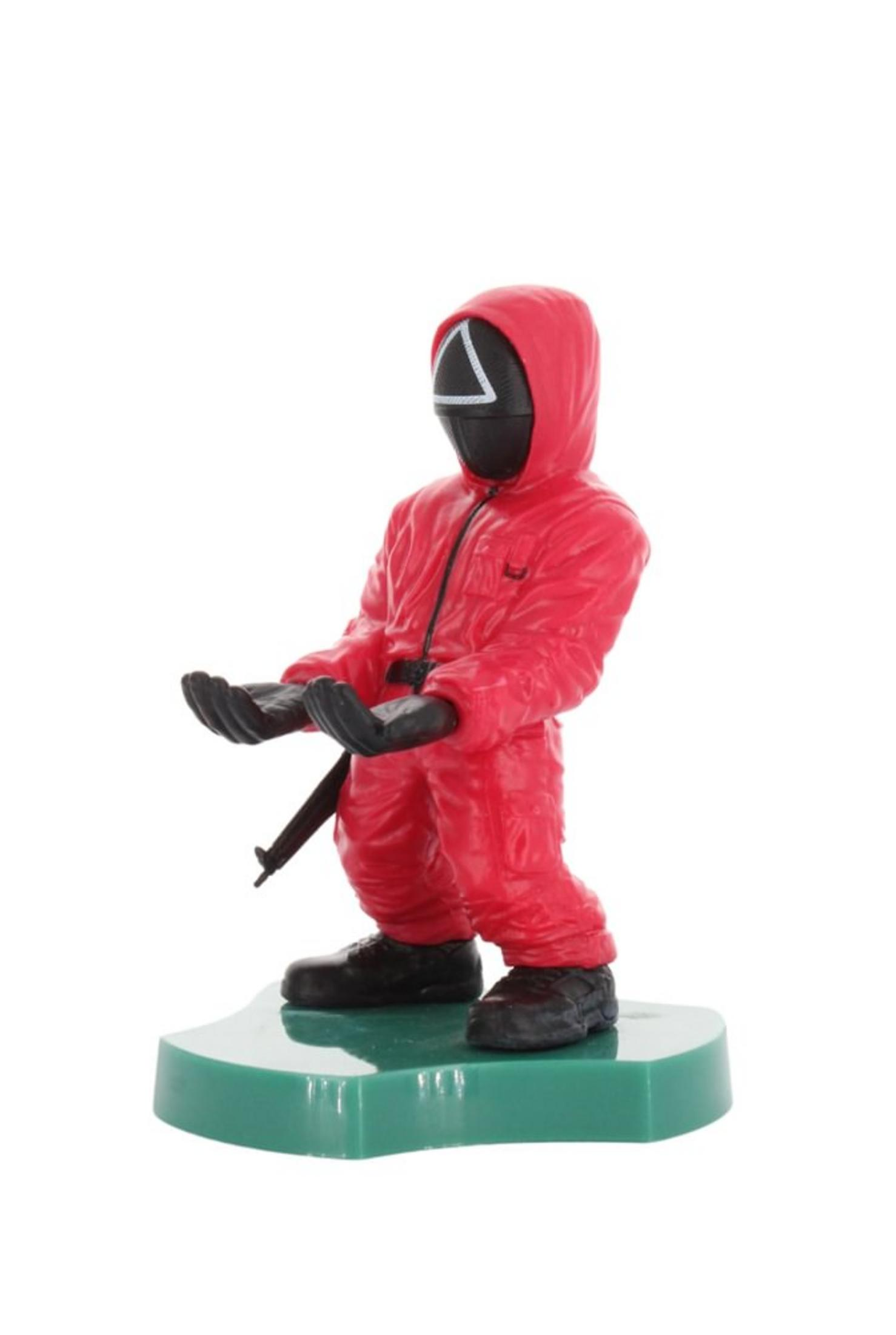 Eine Squid Game-Figur eines maskierten Soldaten auf einem grünen Sockel, bereit, ein Telefon oder einen kleinen Gegenstand zu halten.