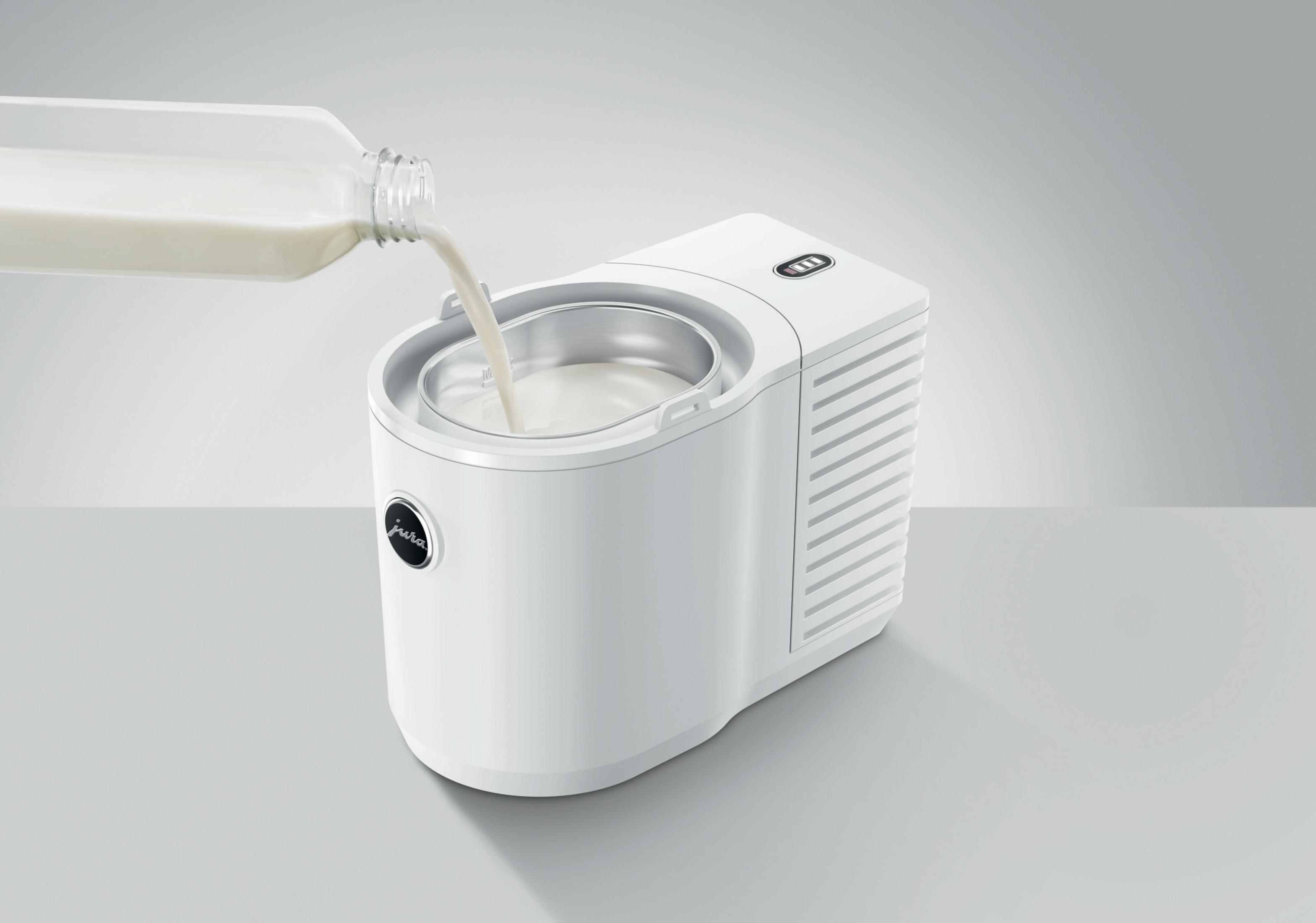 Un contenitore per il latte Jura bianco riempito con latte da una bottiglia di vetro su uno sfondo grigio.