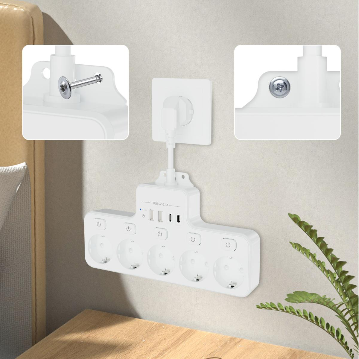 Eine weiße Steckdosenleiste mit USB-Anschlüssen ist an einer Wand neben einer grünen Pflanze montiert.