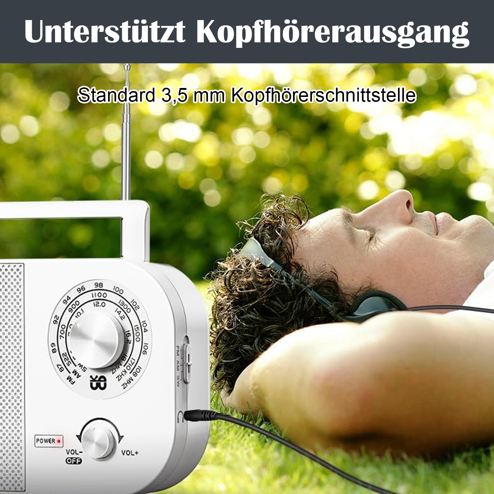 Person, die im Freien im Gras mit Kopfhörern ein weißes tragbares Radio hört.