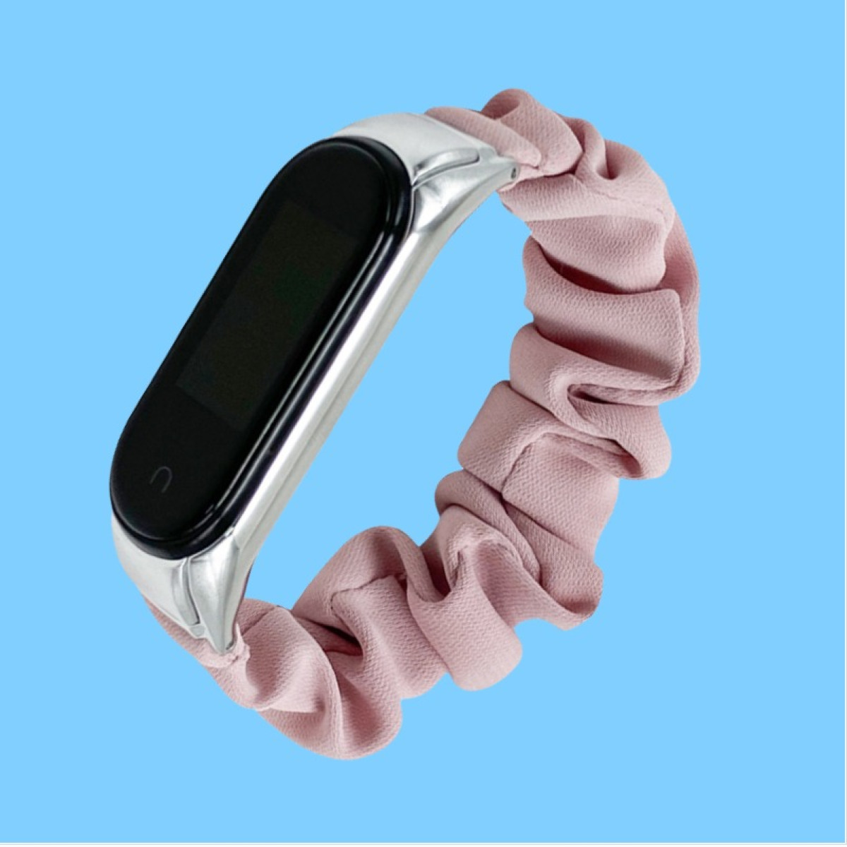 Eine silberne Smartwatch mit schwarzem Bildschirm und rosa Scrunchie-Band auf blauem Hintergrund.