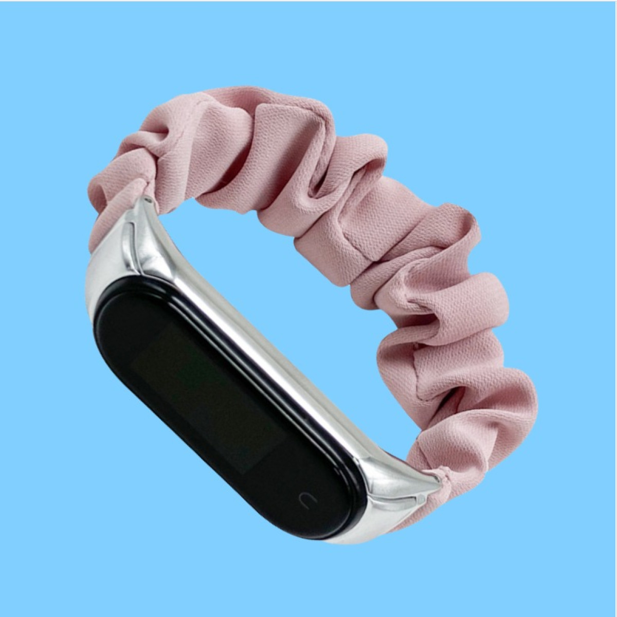 Eine Smartwatch mit schwarzem Bildschirm und rosa Scrunchie-Band auf blauem Hintergrund, schräg gestellt.