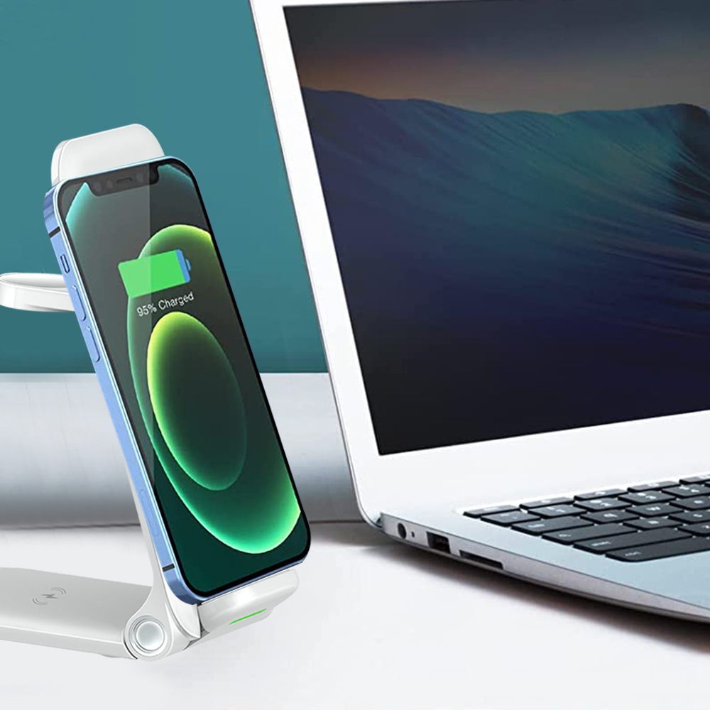Telefon, das auf einem weißen Ständer neben einem Laptop vor einem blaugrünen Hintergrund auflädt.