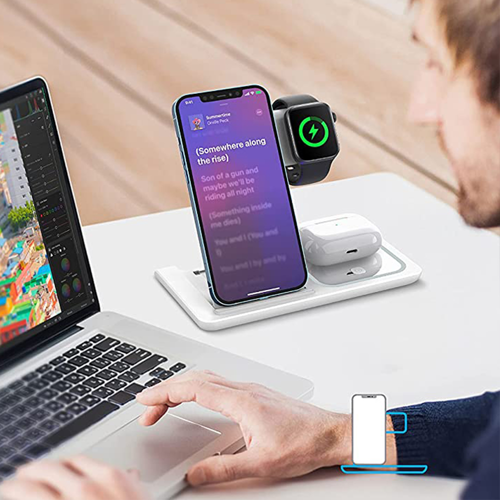 Ein Mann arbeitet an einem Laptop mit einer kabellosen Ladestation für Telefon, Uhr, Ohrhörer.
