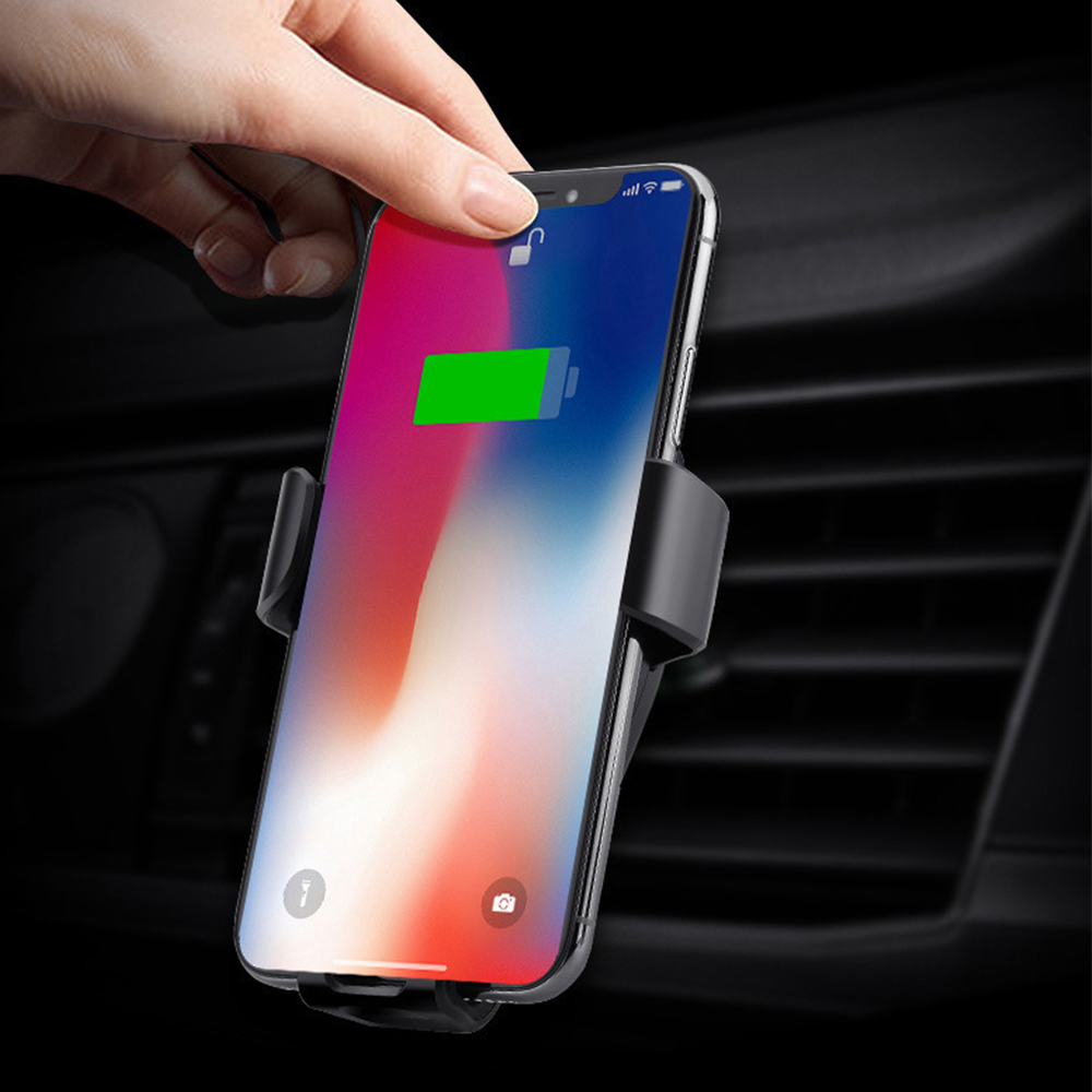 Eine Hand platziert ein Smartphone mit einem sichtbaren grünen Ladesymbol in eine Autotelefonhalterung.